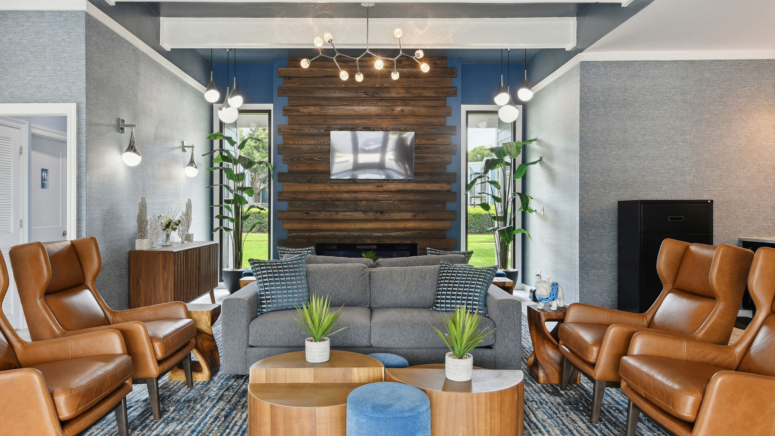 Inviting living area with chic decor, modern lighting, and lush greenery, showcasing elegant leather chairs and a cozy sofa.