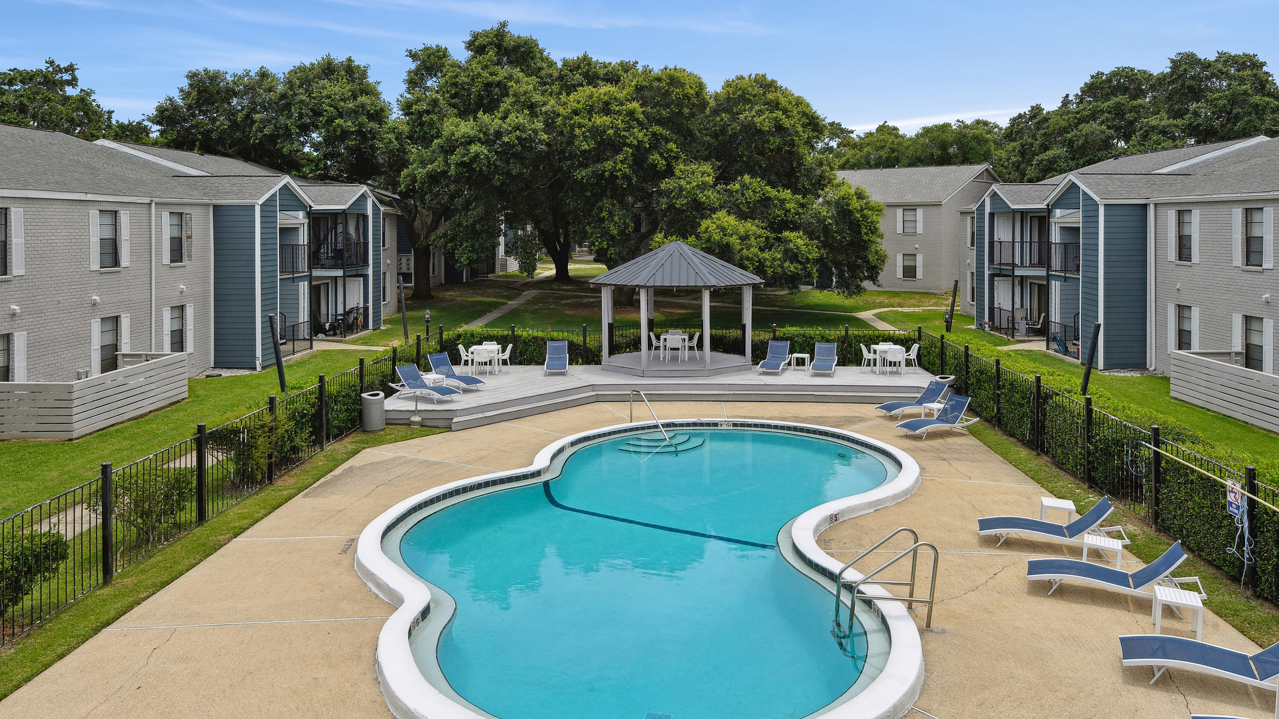 Inviting apartment complex featuring a beautifully designed pool, surrounded by lush greenery and modern lounges, ideal for relaxation and leisure.