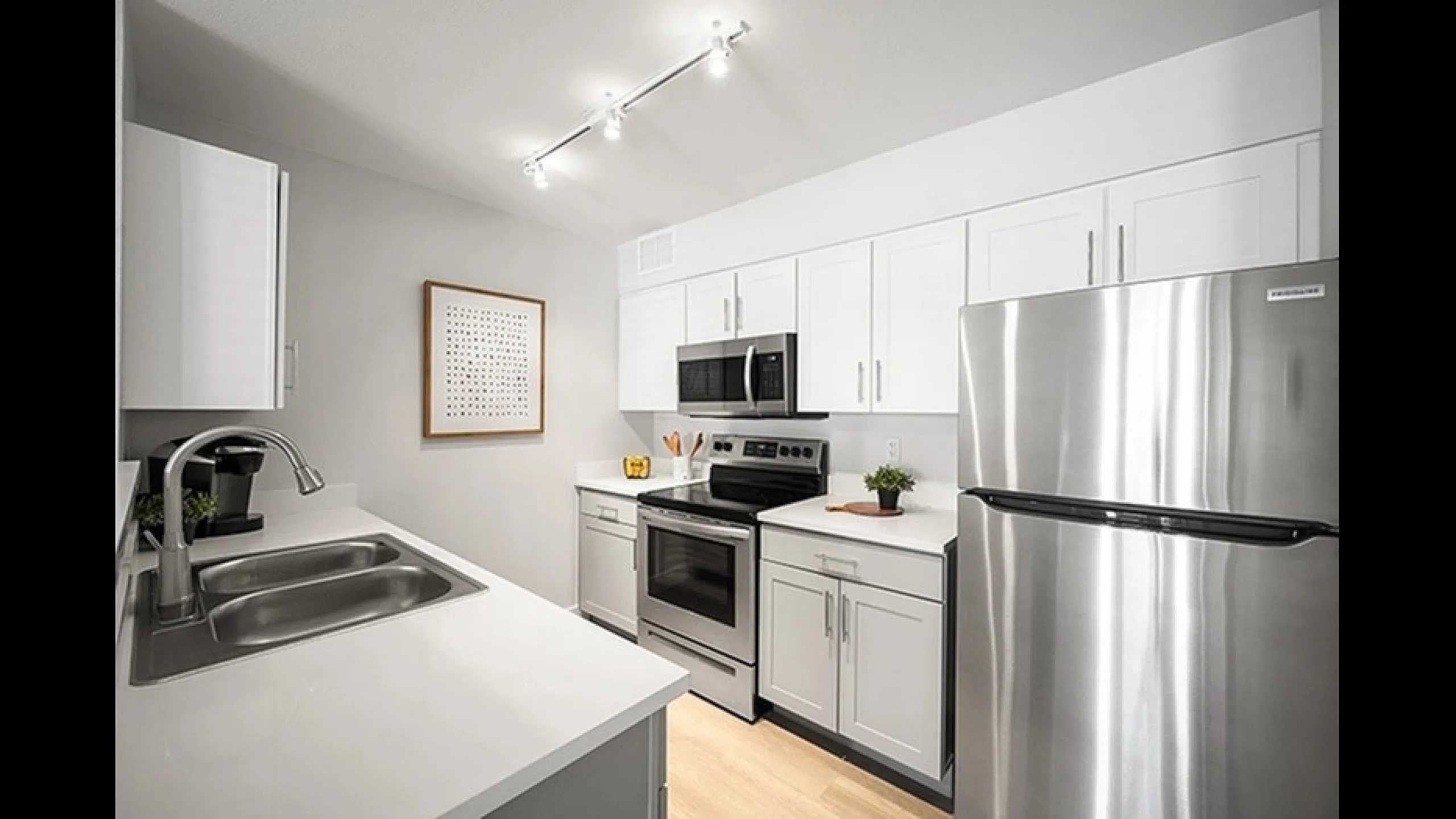 Modern, sleek kitchen with white cabinetry, stainless steel appliances, and chic lighting, offering a contemporary culinary space.