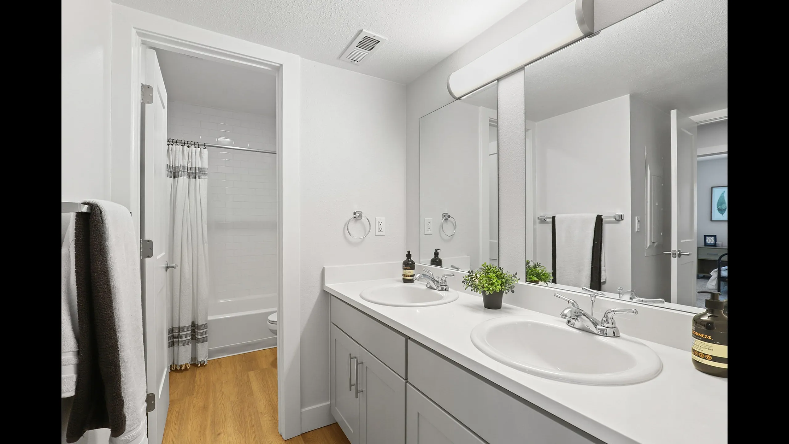 Modern bathroom with dual sinks, elegant white countertops, and inviting bathtub, exuding a sleek and sophisticated ambiance.