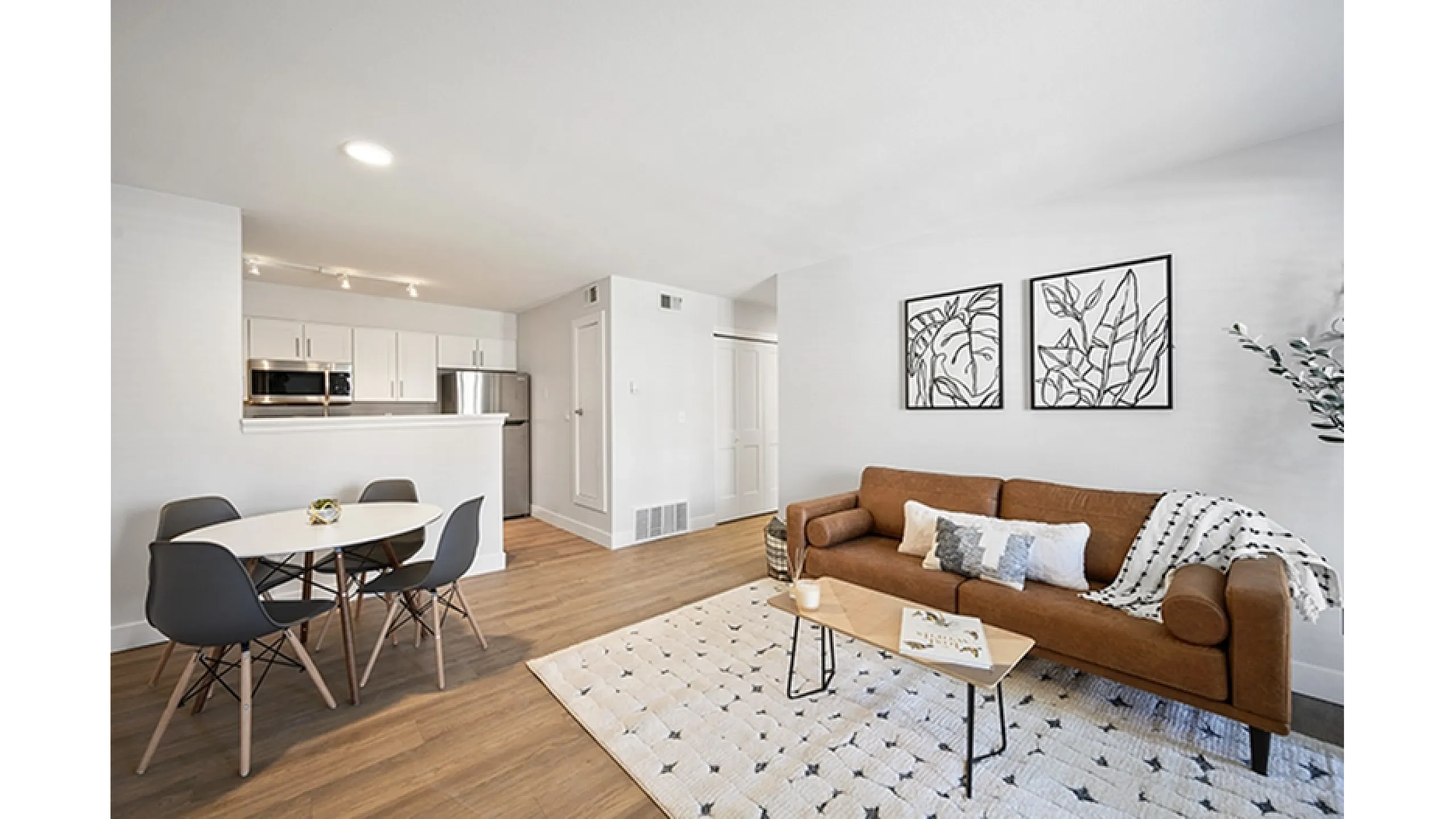 Modern living space showcasing a cozy brown sofa, stylish dining area, and sleek kitchen with stainless steel appliances.