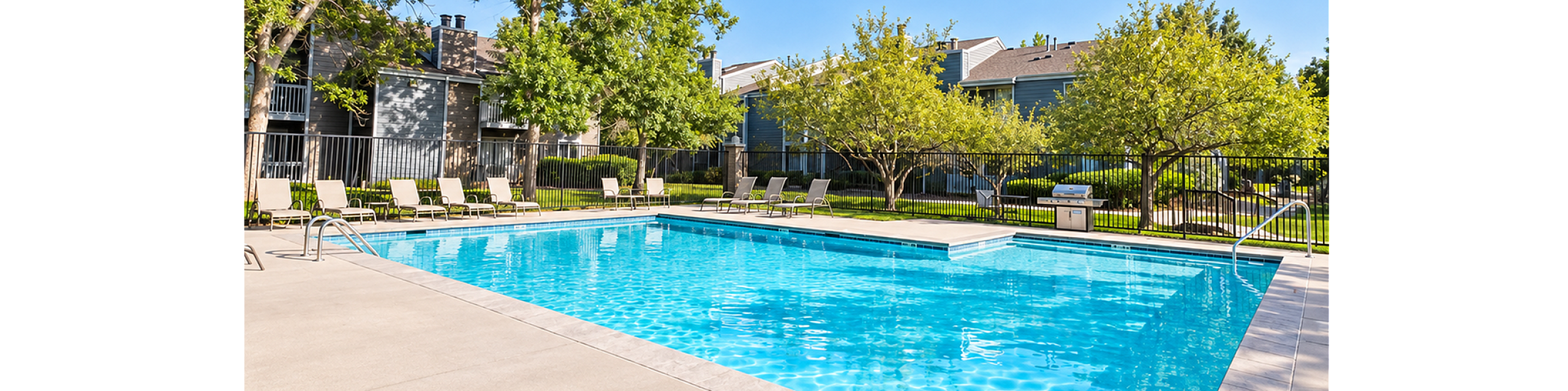 Inviting outdoor pool area with clear blue water, surrounded by lush greenery and comfortable lounge chairs, perfect for relaxation.