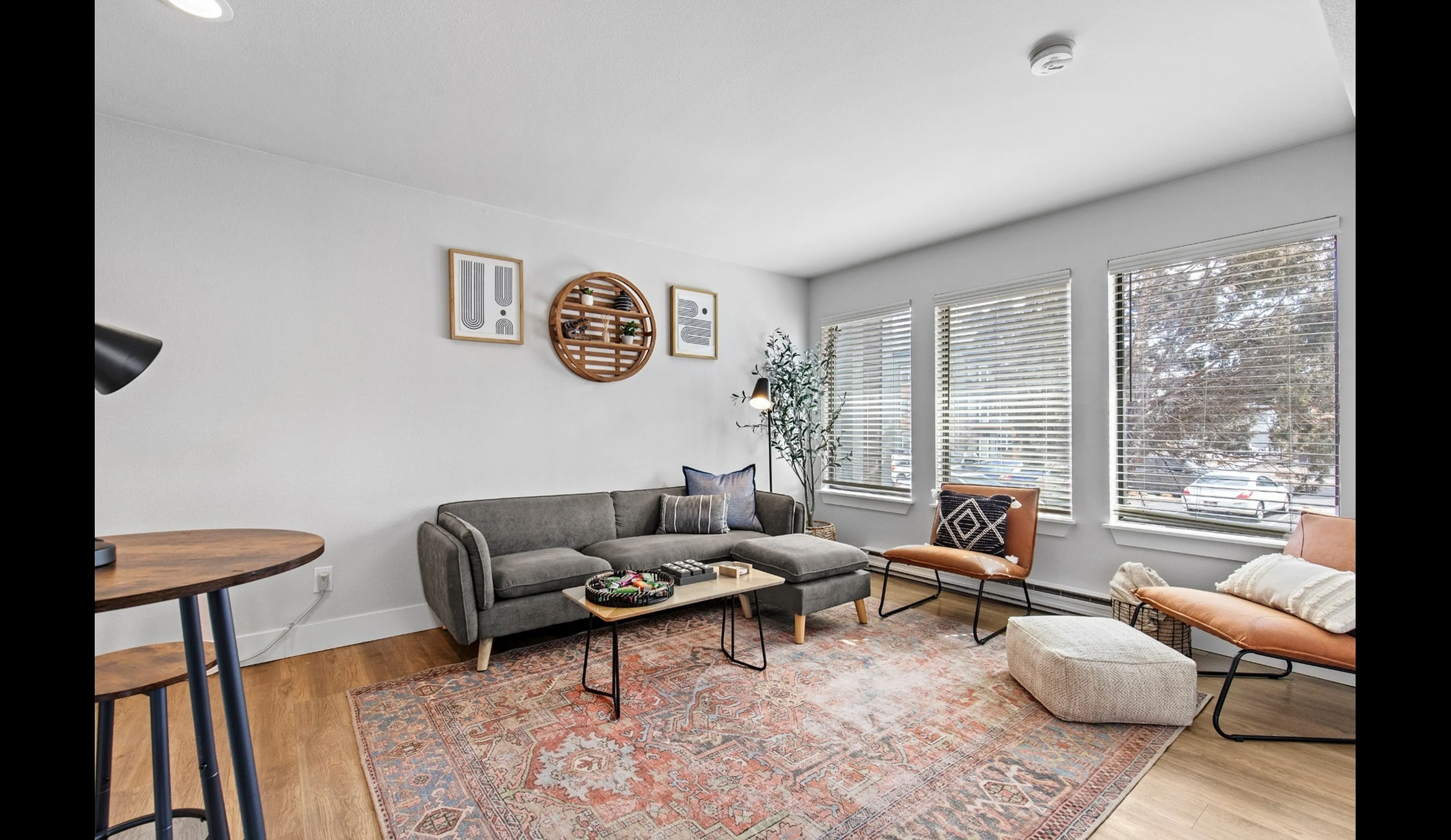 Bright and inviting living room with a modern gray sectional sofa, decorative cushions, and large windows for natural light.