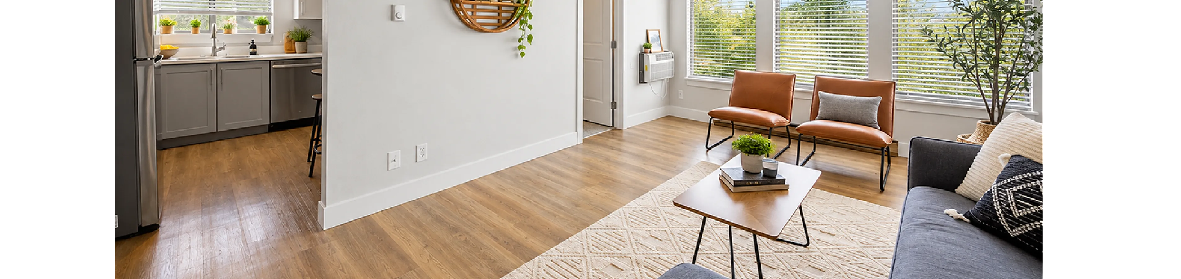 Bright and modern living room with large windows, featuring stylish decor and a cozy atmosphere adjacent to an open kitchen.