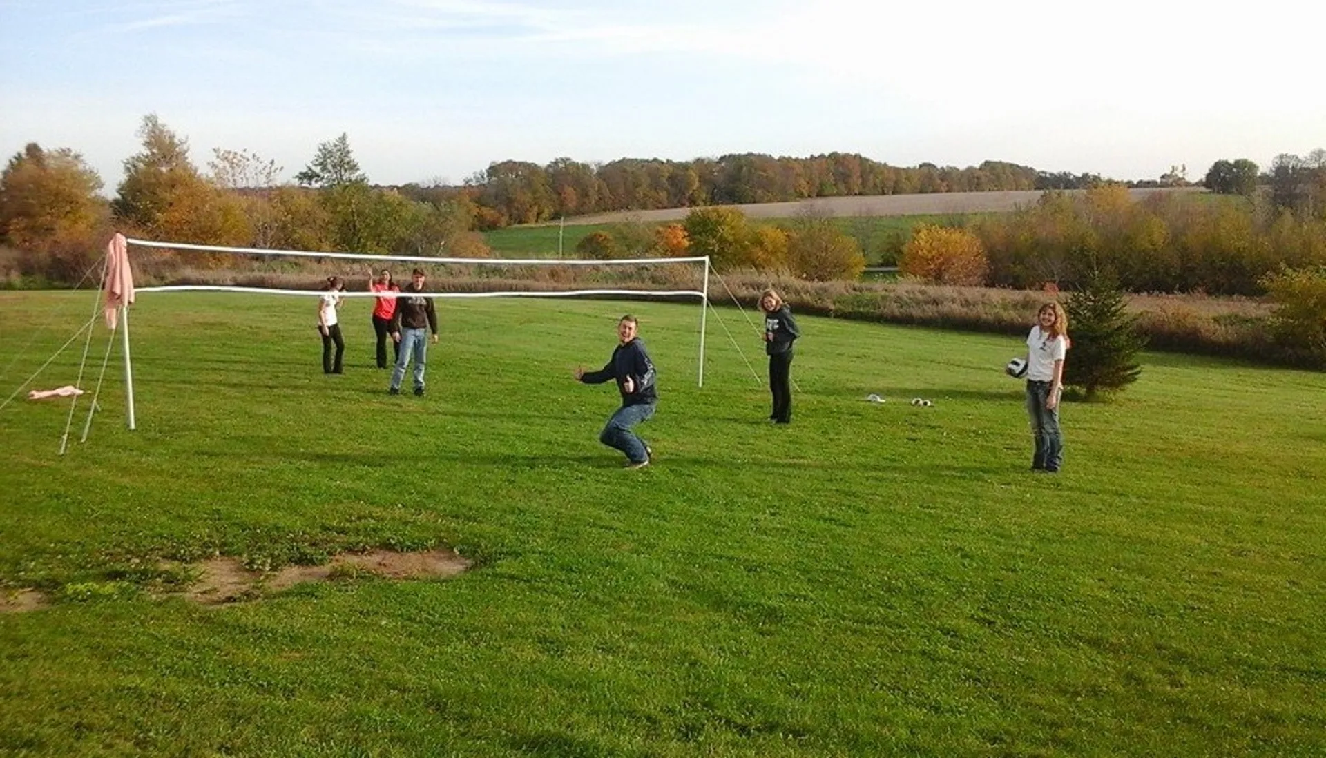 Students smiling and waving as they play Volleyball