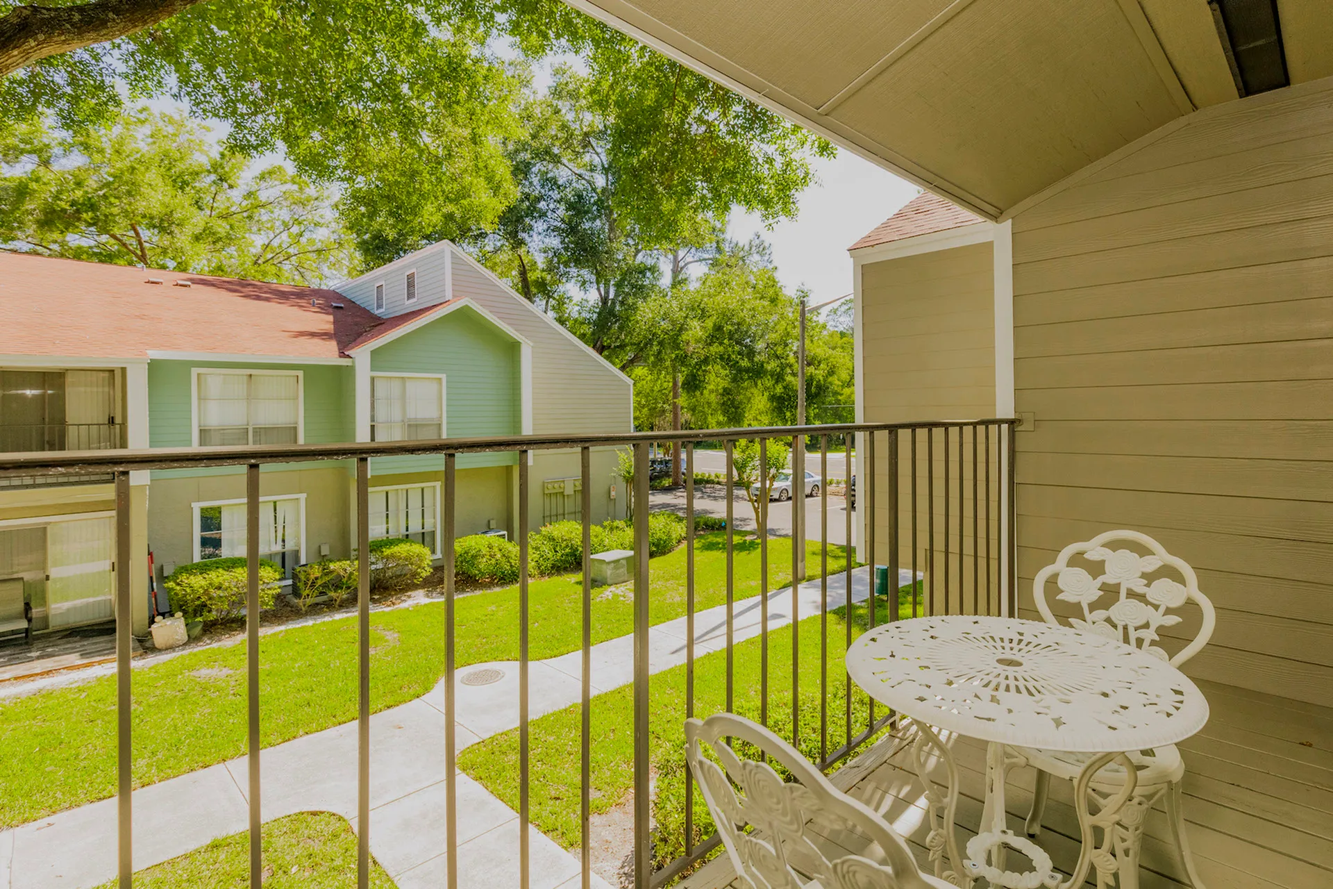 Bedroom balcony overlooking the community. There is a sidewalk surrounded by green space that leads to each apartment entrance.