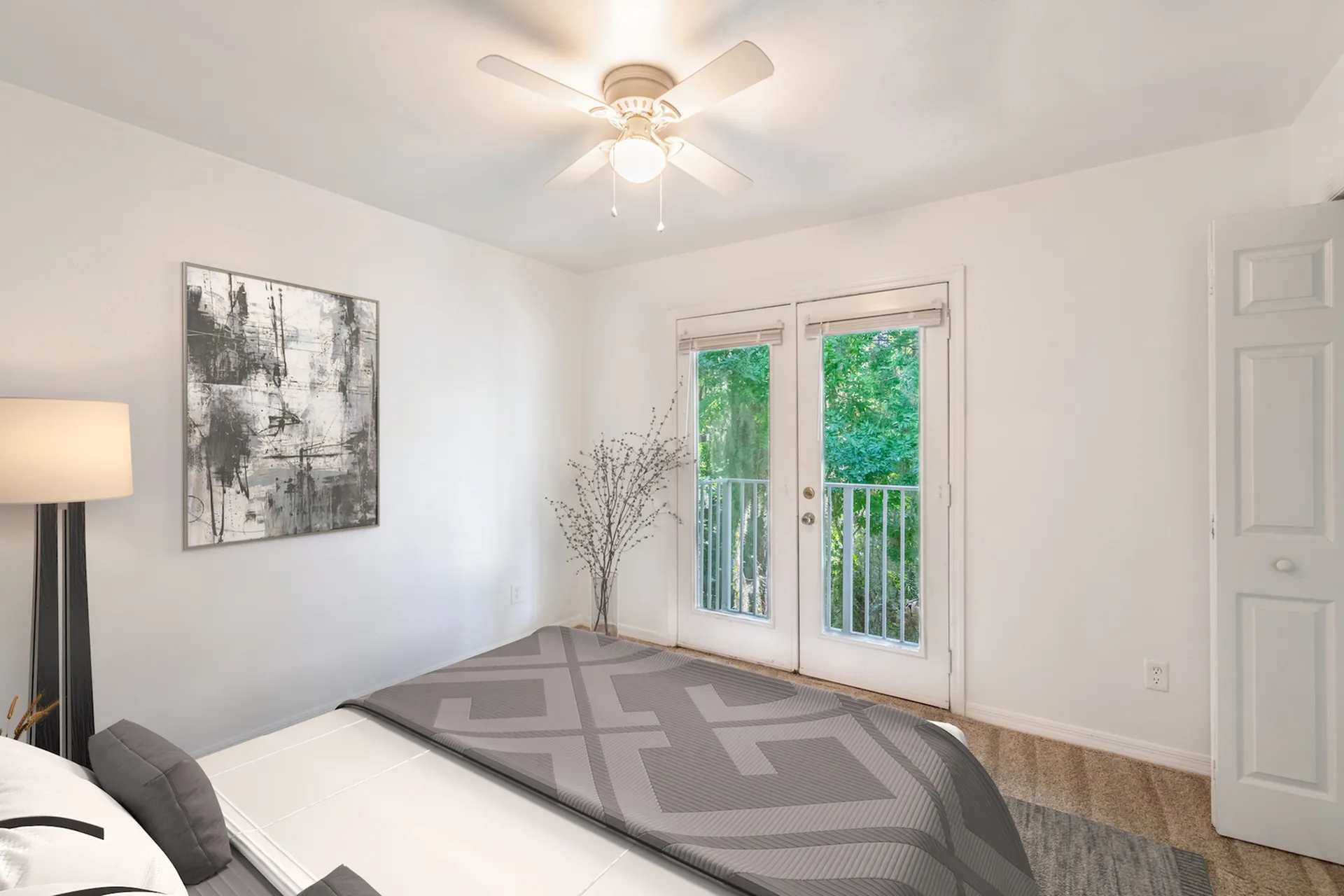 Carpeted bedroom with white walls, doors leading to an outdoor balcony.