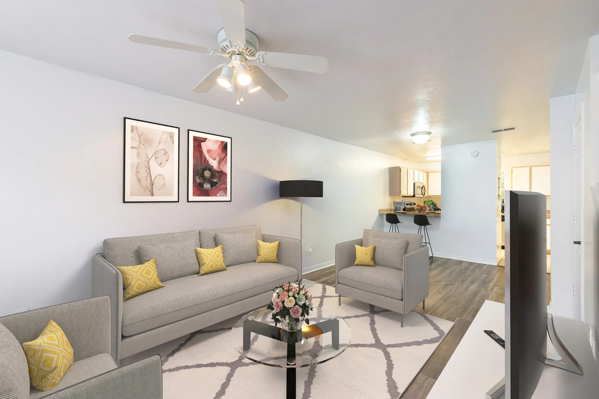 Close up of living room area with three couches, wall art, circular glass coffee table. You can see the kitchen and passthrough in the background to the right.