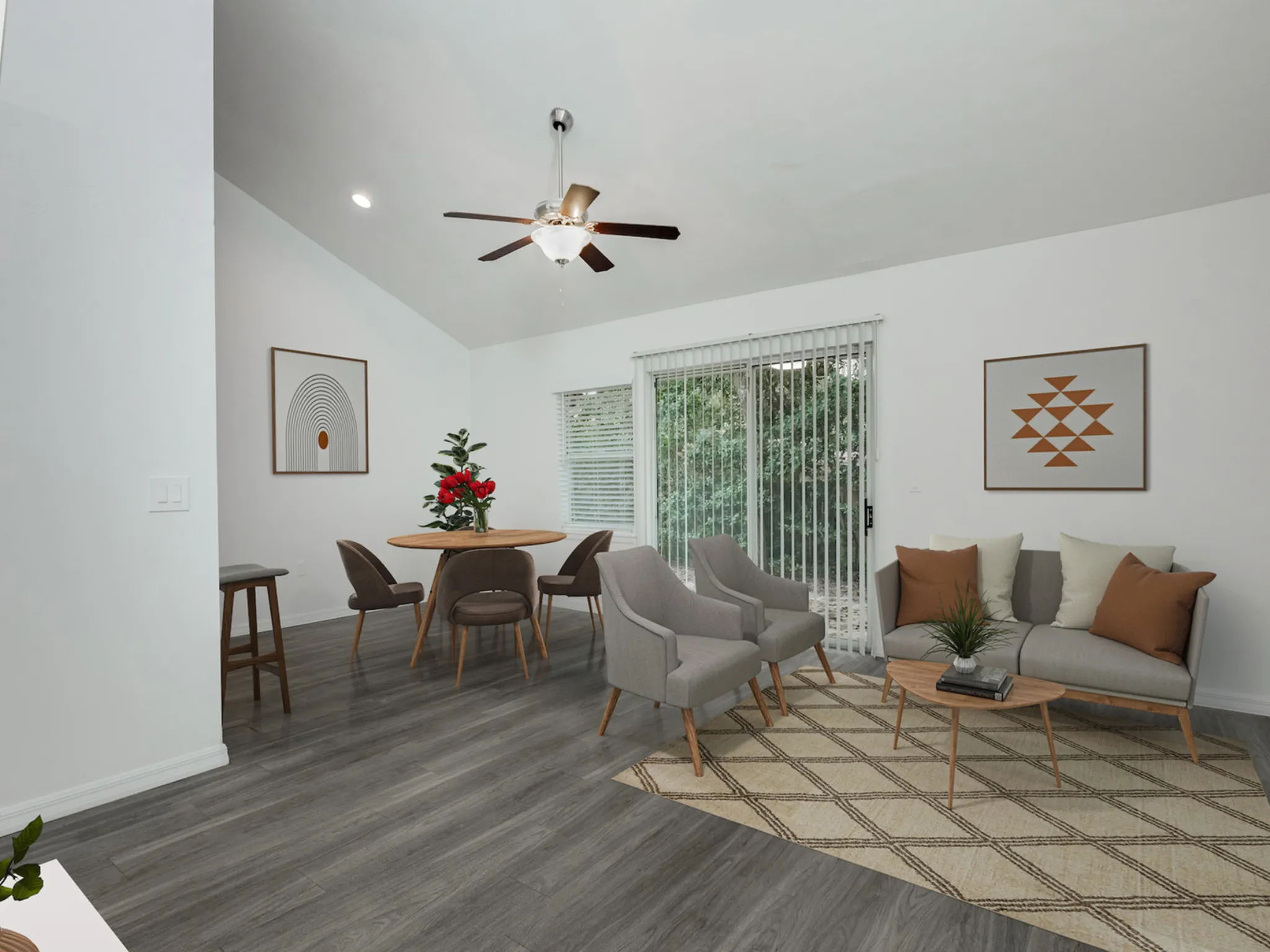 Living and dining area with chairs, table, loft ceiling and patio doors.