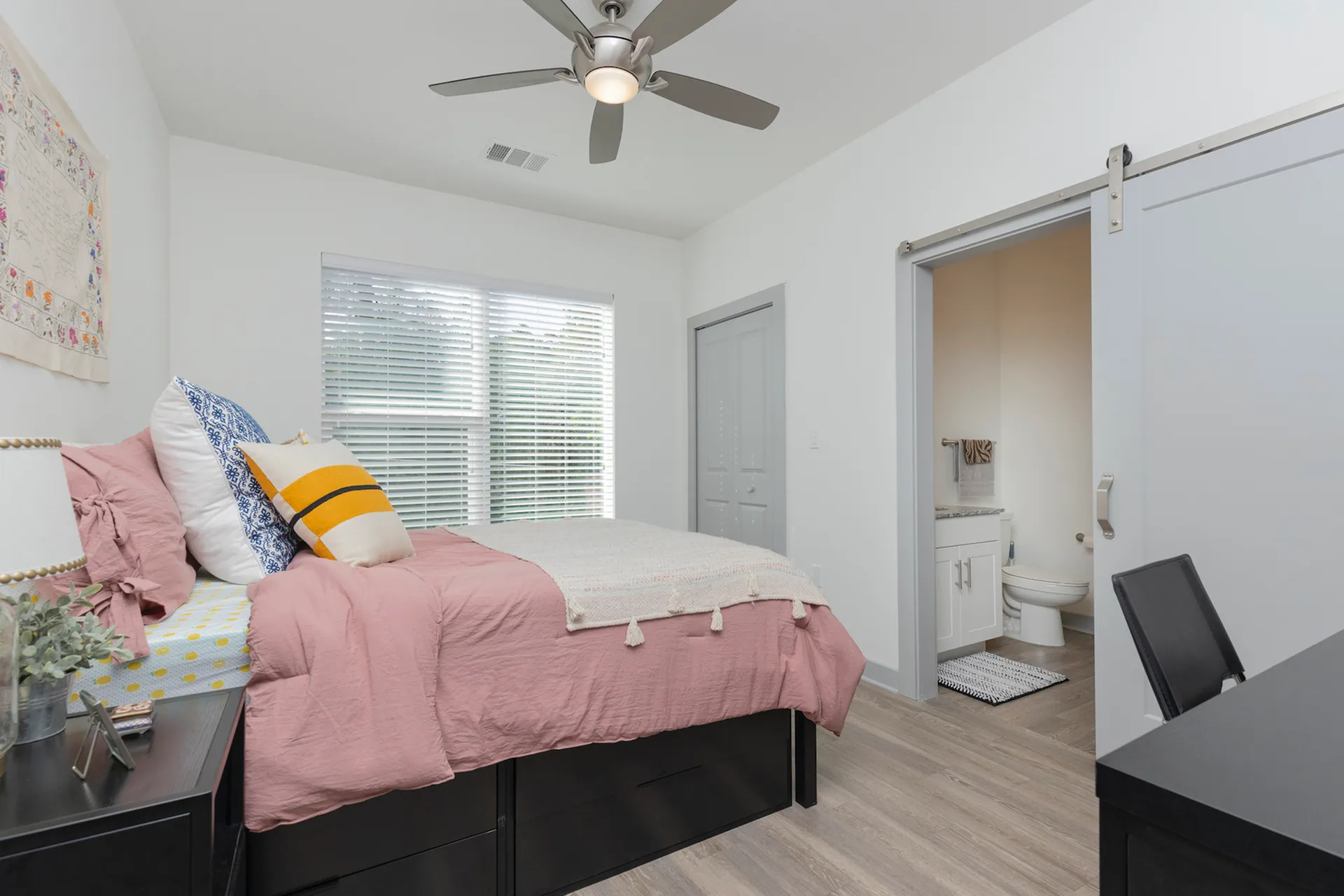 Living room with hardwood floors, desk with chair, ceiling fan, access to bathroom, and access to the main living area.