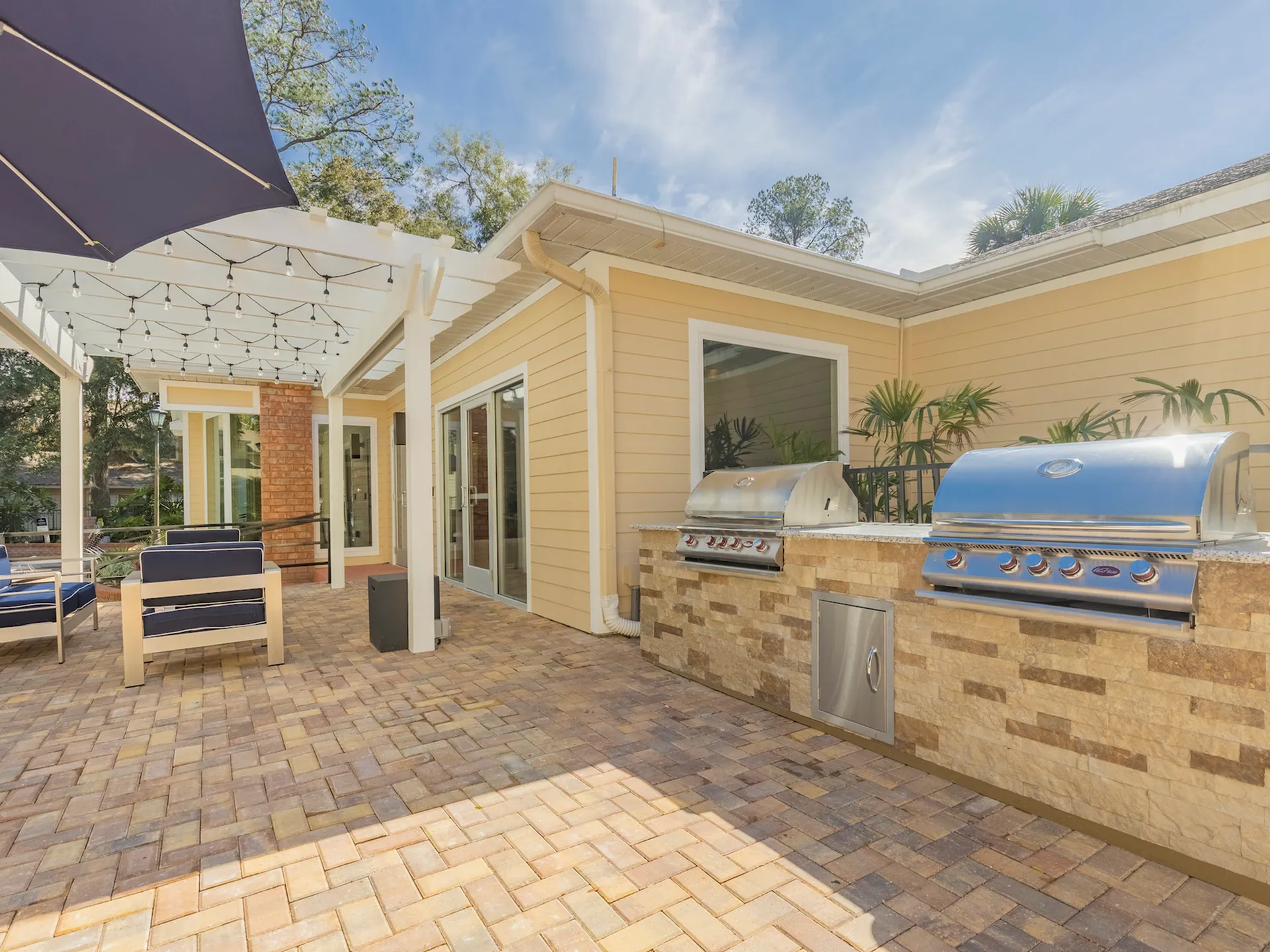 Barbecue area next to the patio seating at the community pool. there are two stainless steel barbecues as well as counter space.