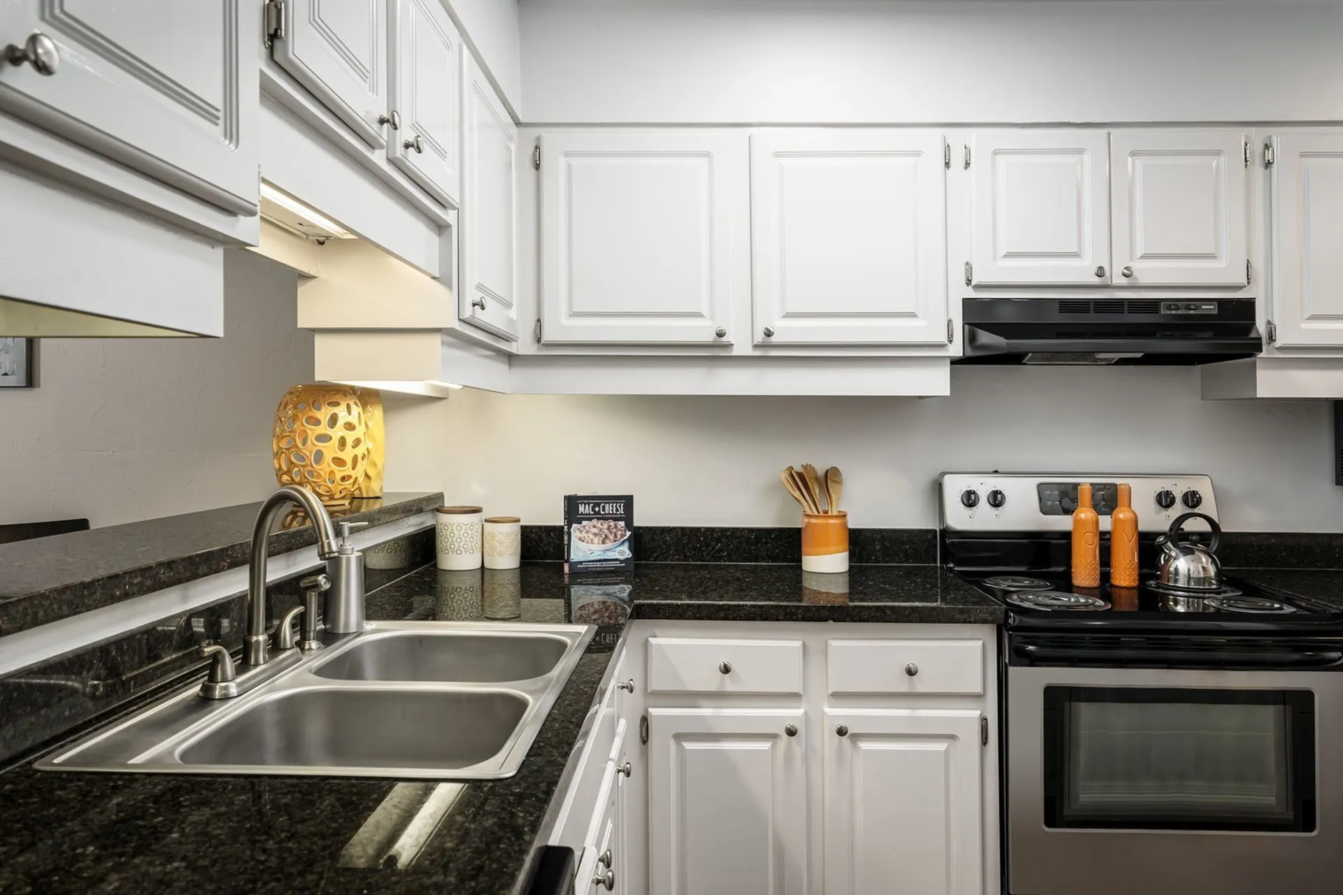 Kitchen with black granite countertop, white classic cabinets, and stainless steel oven