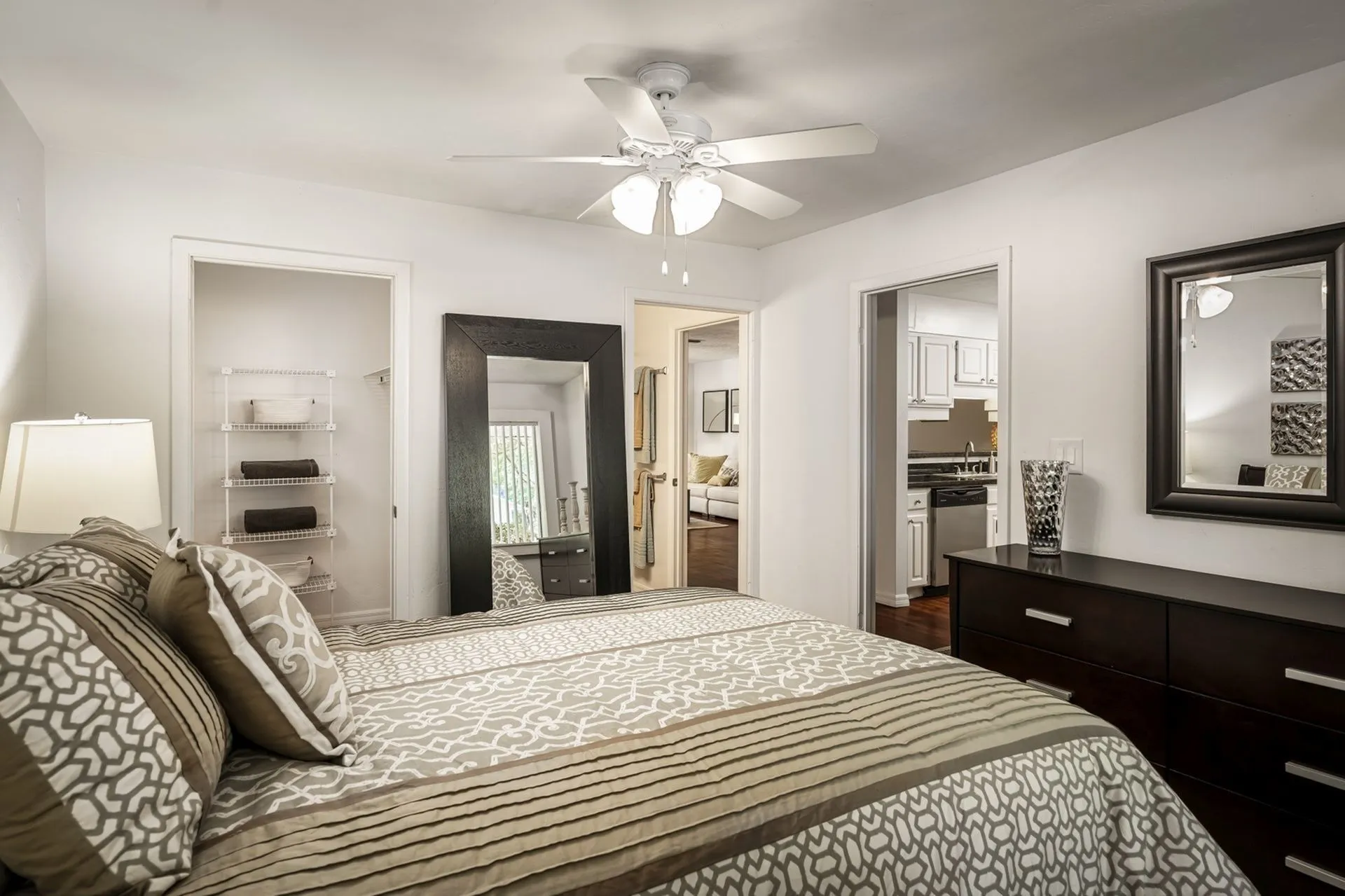 Bedroom with large queen bed, closet, full mirror and dresser.