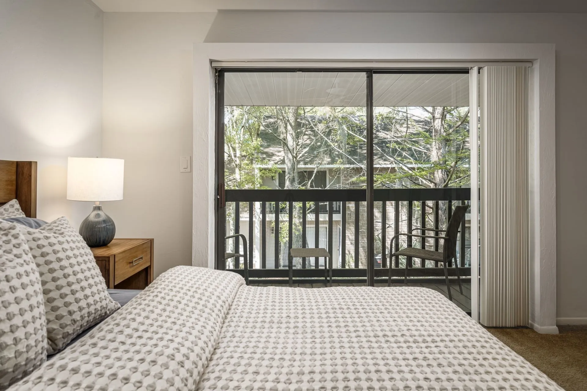Carpeted bedroom with queen bed, rustic furniture and sliding glass door overlooking balcony.