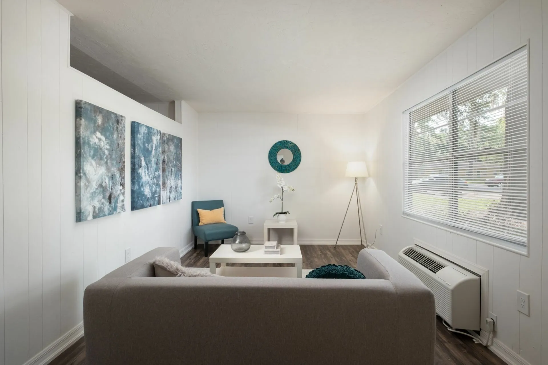 Living room with gray couch, air conditioning and wall art