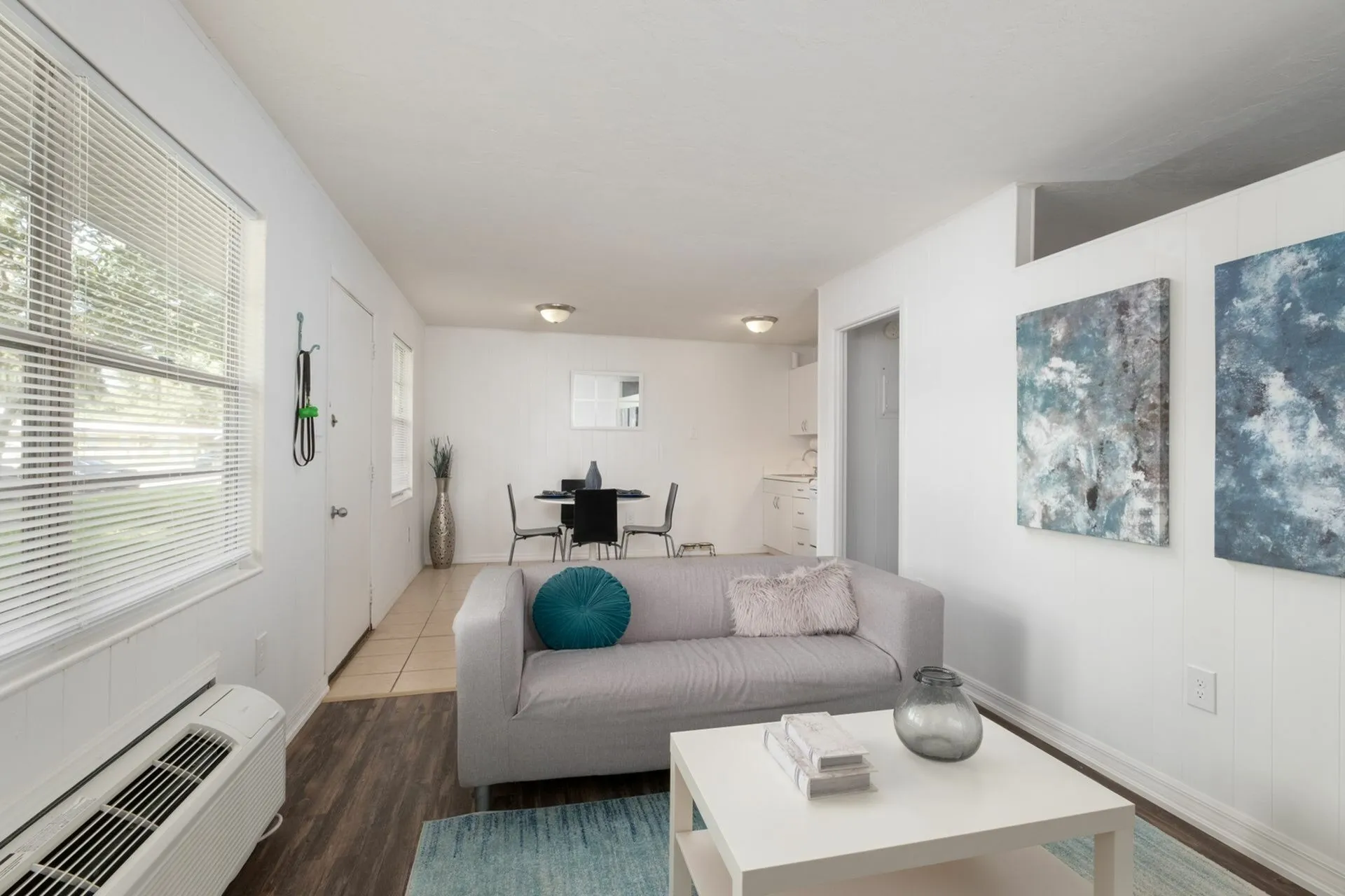 Living room with gray couch, air conditioning and wall art