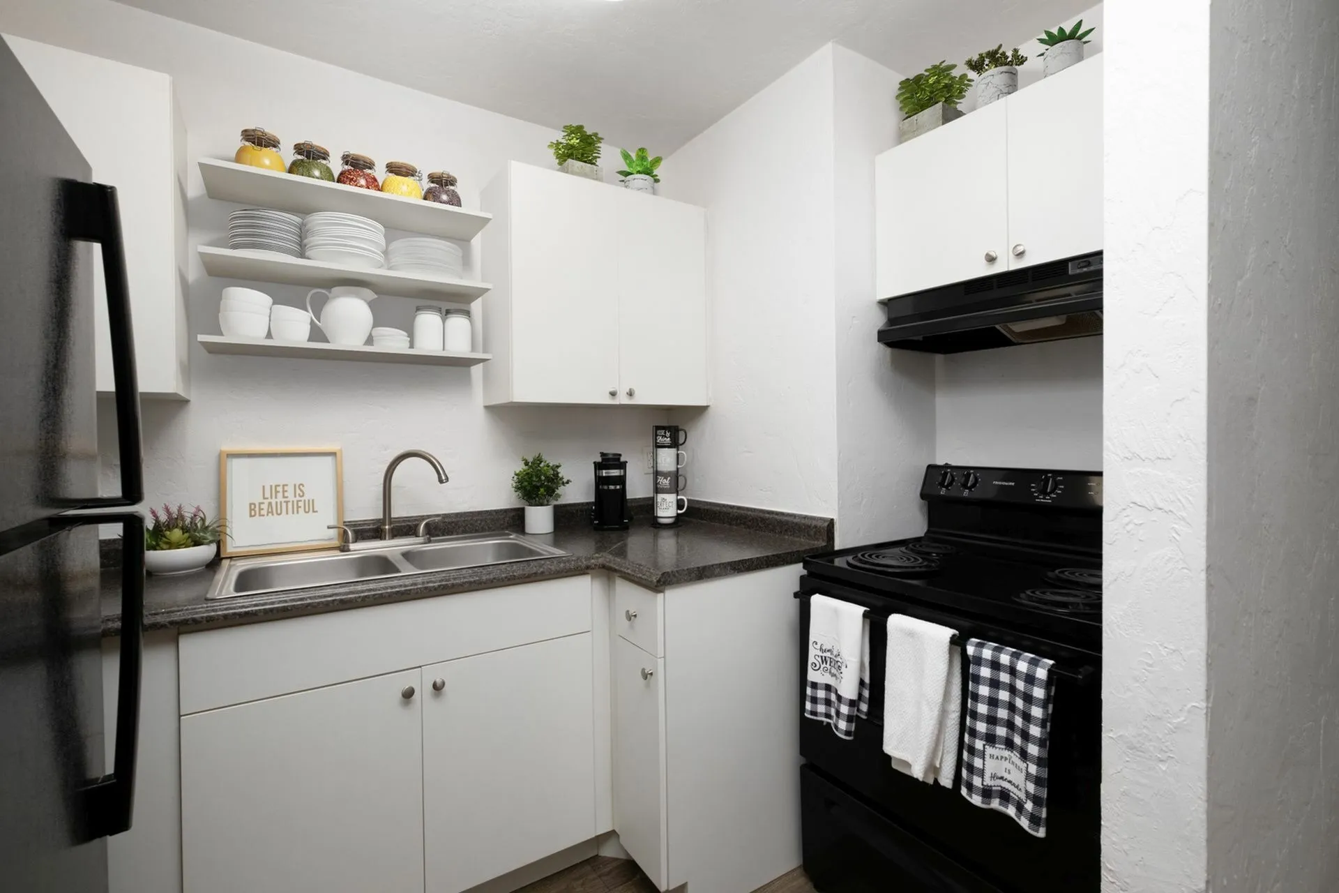 Kitchen with white cabinets, black and grey countertops, and white appliances.