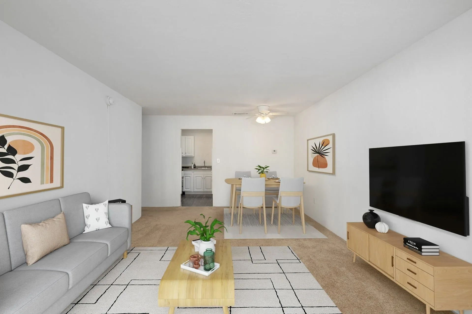 Carpeted living area with modern furniture, television, and wall art.