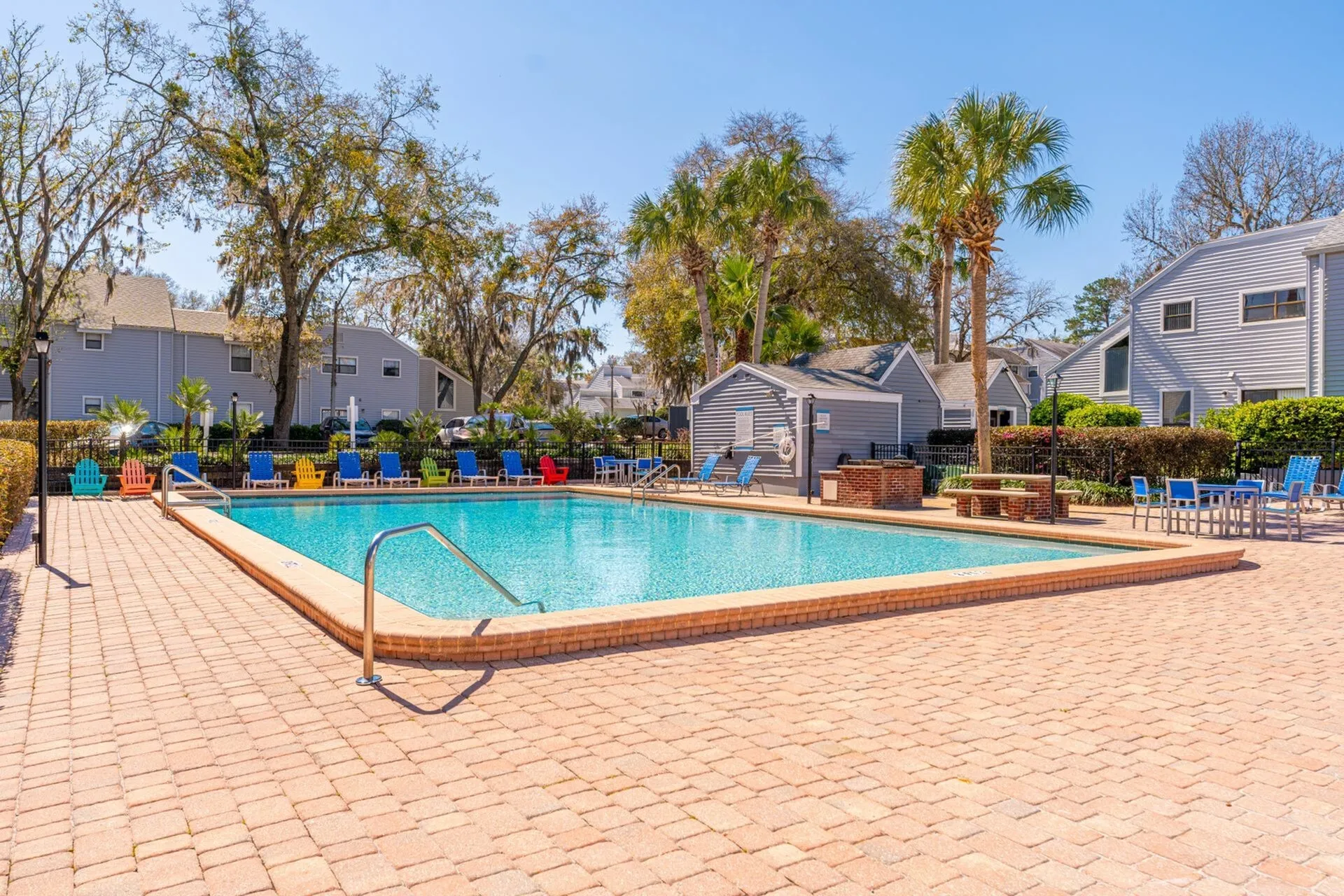 Rectangular pool with leasing office and beautiful blue sky in background.
