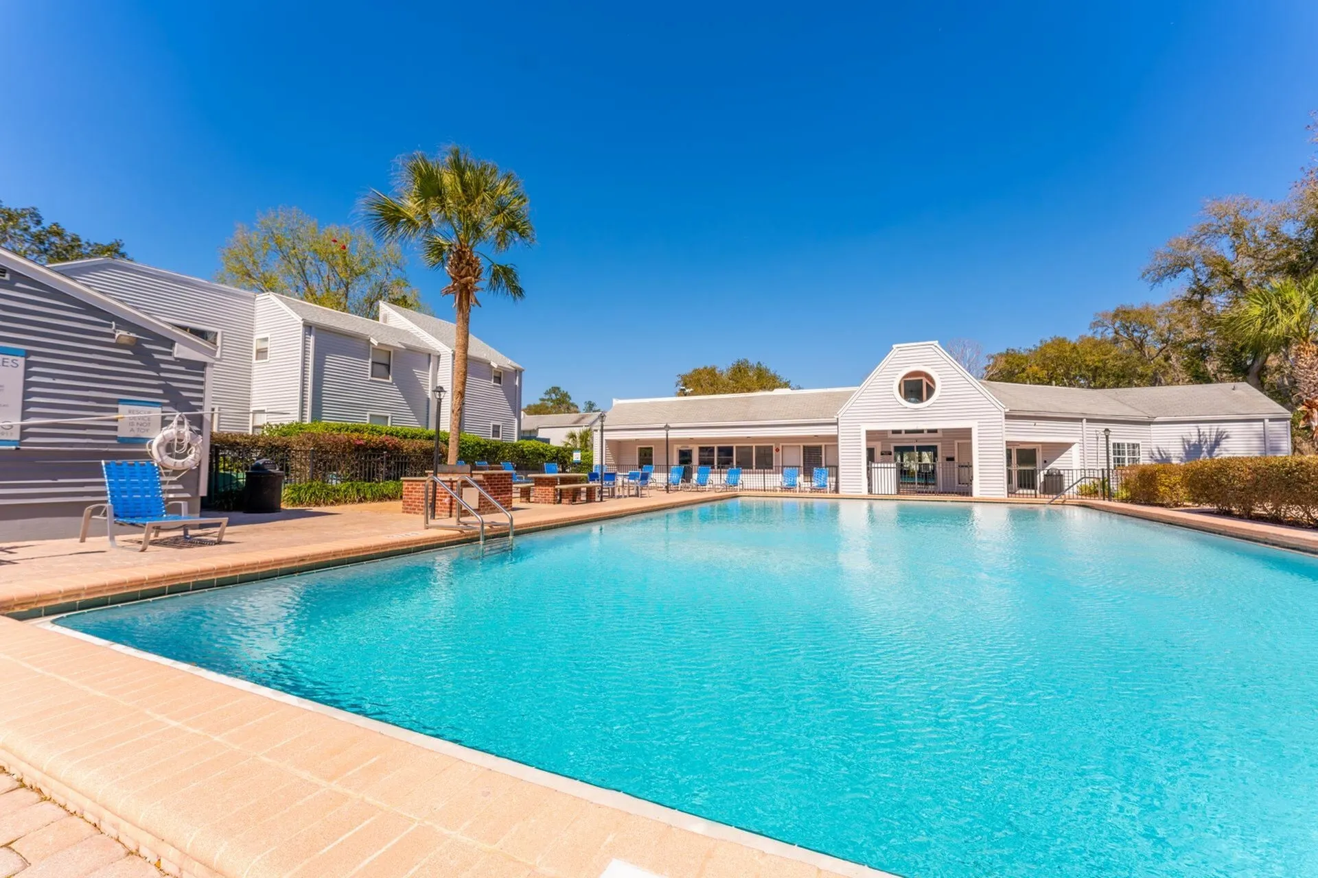 Rectangular pool with leasing office and beautiful blue sky in background.