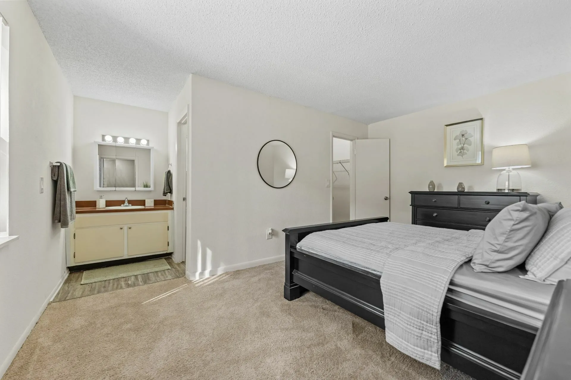 Carpeted bedroom with modern furniture. Ensuite half bathroom in the background