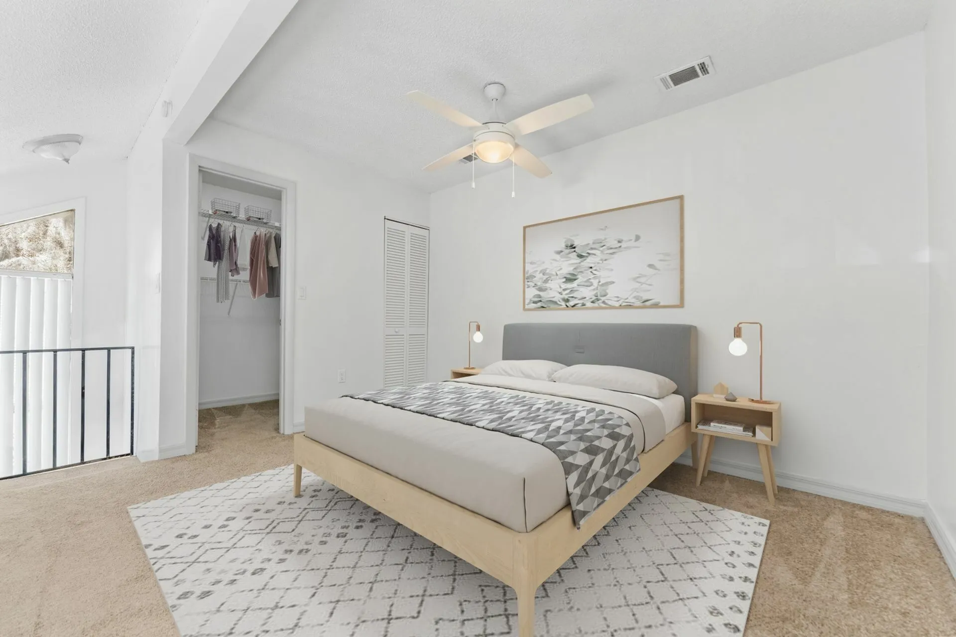 Carpeted bedroom with modern furniture. There is a large window exposing the exterior green space and parking lot.