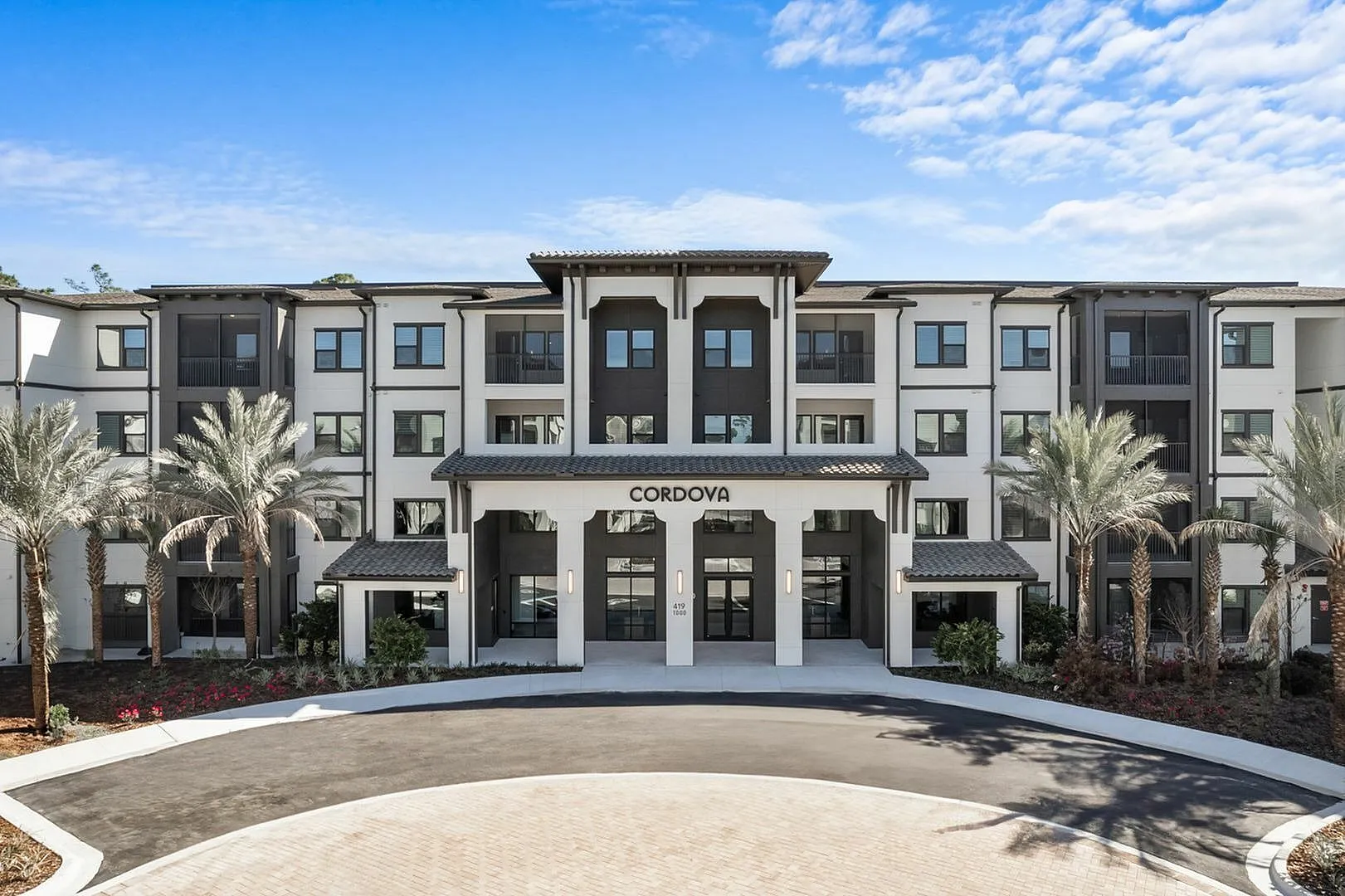 Elegant exterior view of modern Cordova apartments with palm trees and a clear blue sky.