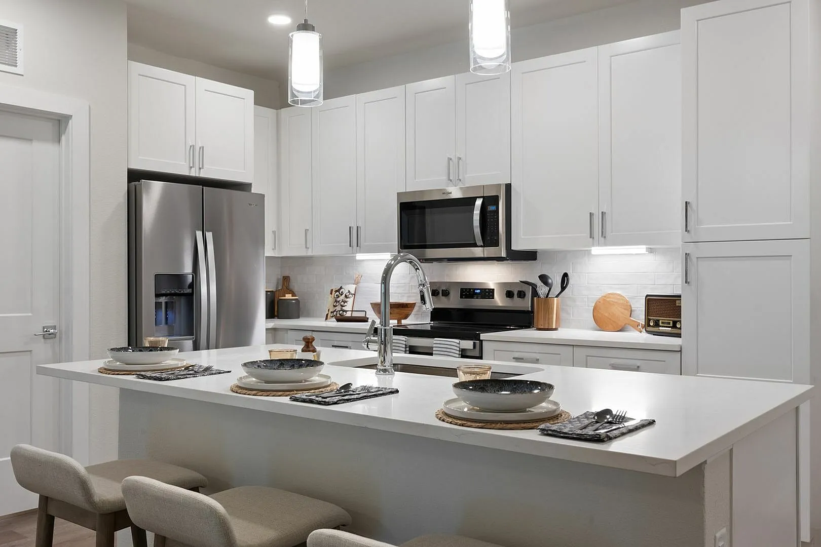 Contemporary kitchen with white cabinets, stainless steel appliances, and a chic breakfast bar.