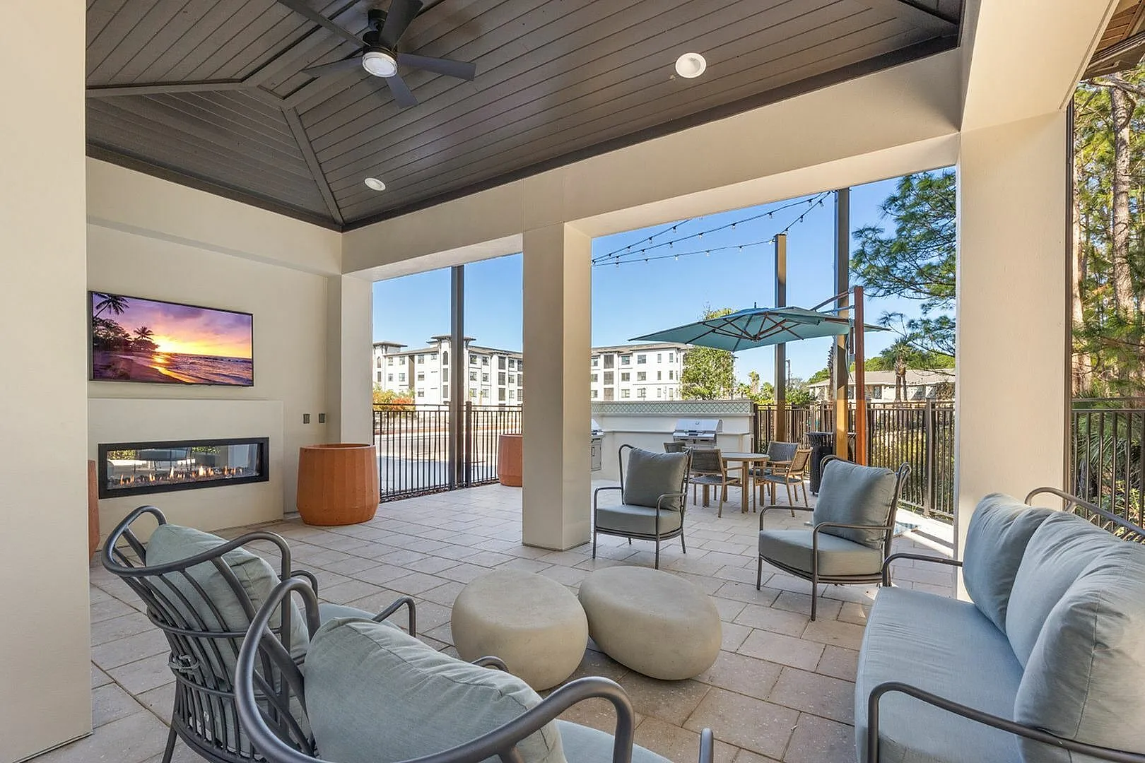 Stylish outdoor lounge area with modern seating, a television, and a cozy fireplace.