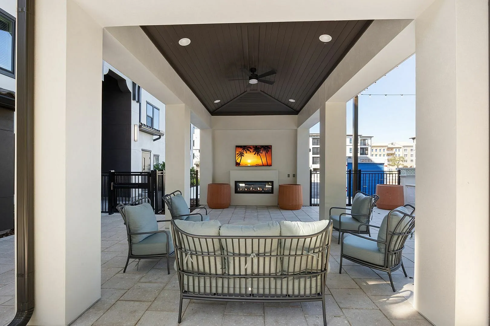 Chic outdoor lounge area with modern seating, large TV, and ambient fireplace.