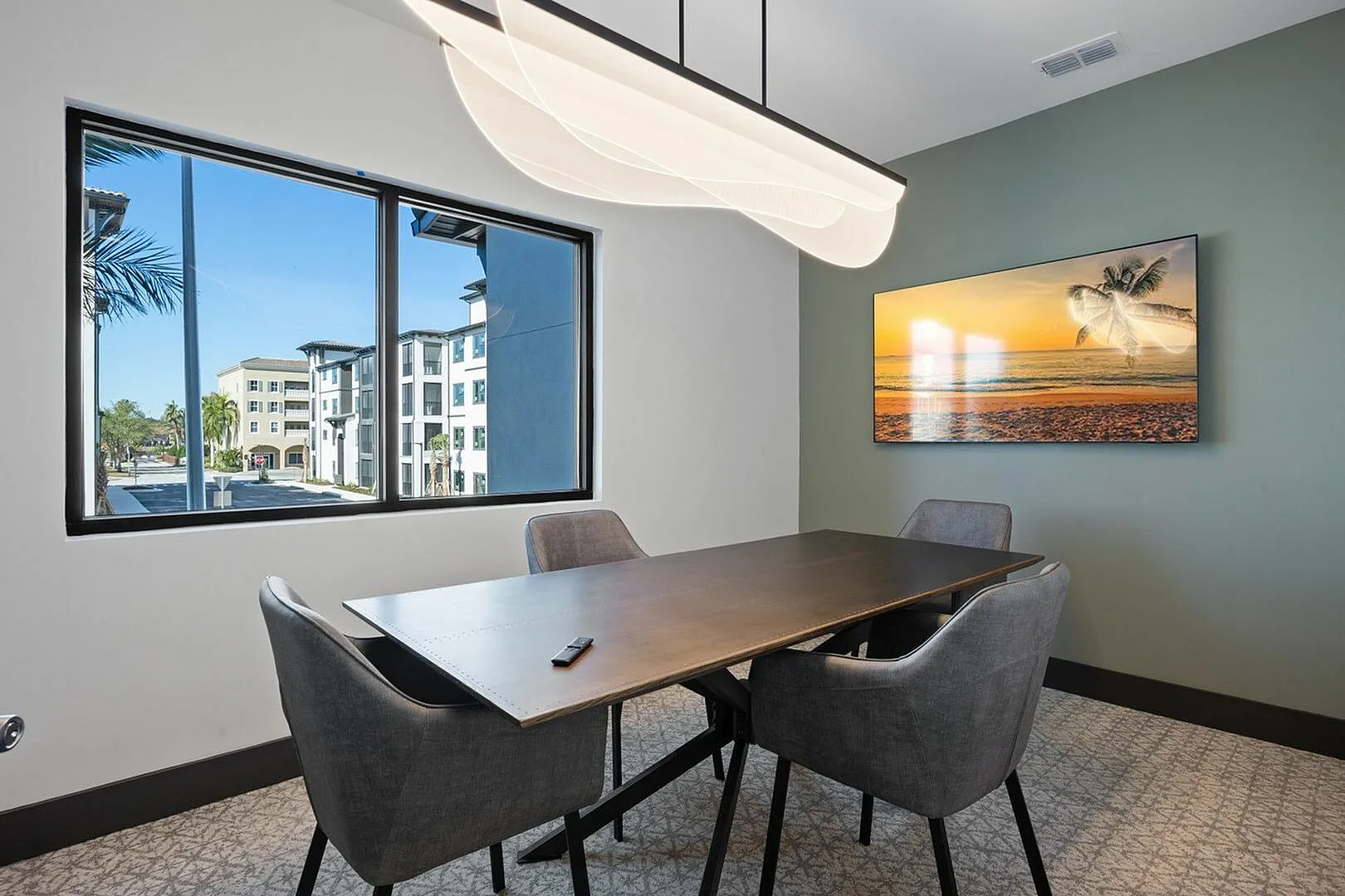 Stylish meeting room with modern furniture and a large window offering a view of contemporary apartments.