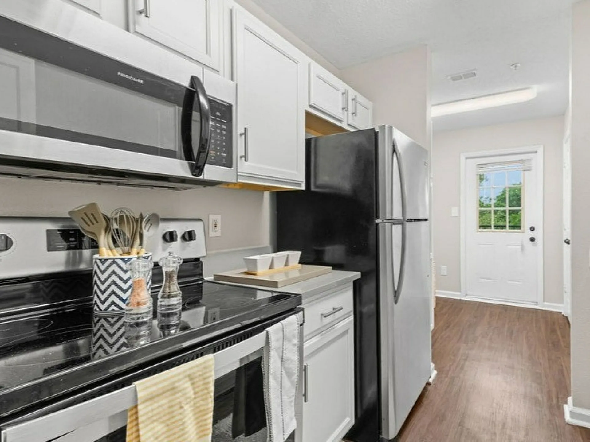 Modern kitchen with sleek stainless steel appliances, ample cabinetry, and elegant hardwood flooring, bathed in natural light.