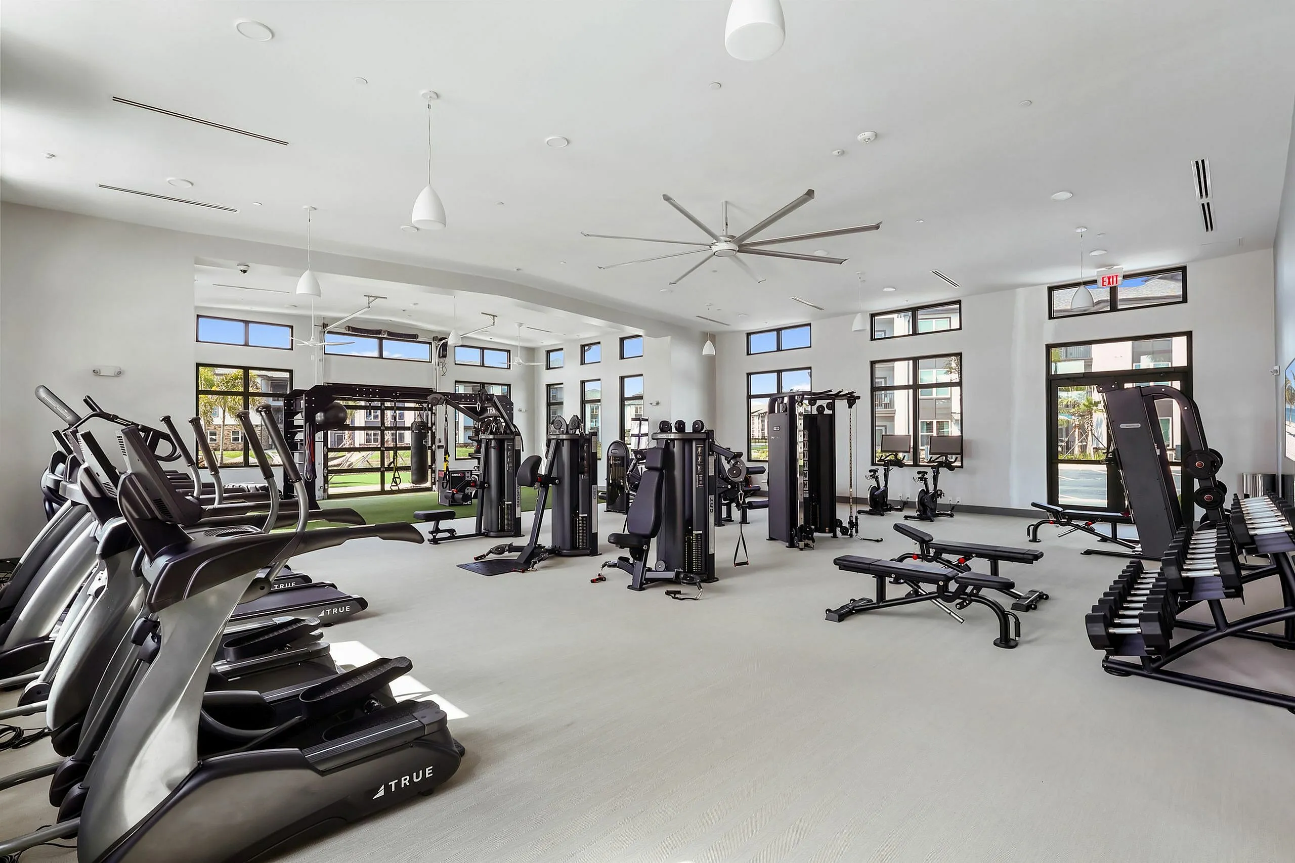 Spacious state-of-the-art fitness center with modern equipment, abundant natural light, and sleek design.