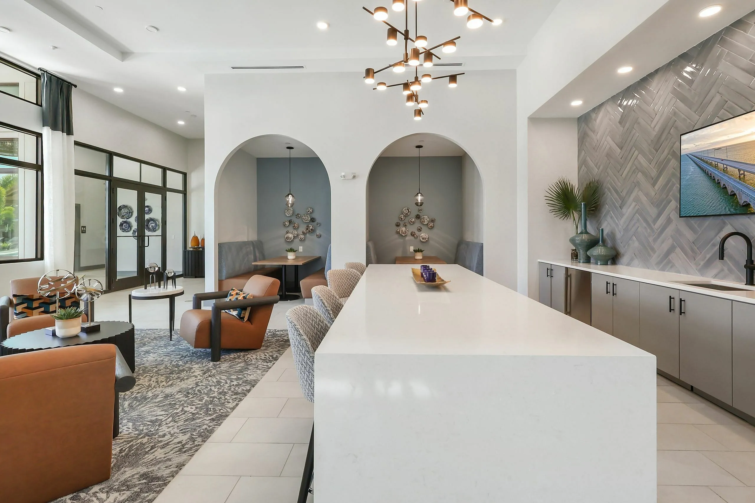 Modern open-concept living space featuring elegant seating, stylish decor, and a chic kitchen area with herringbone backsplash and unique lighting.