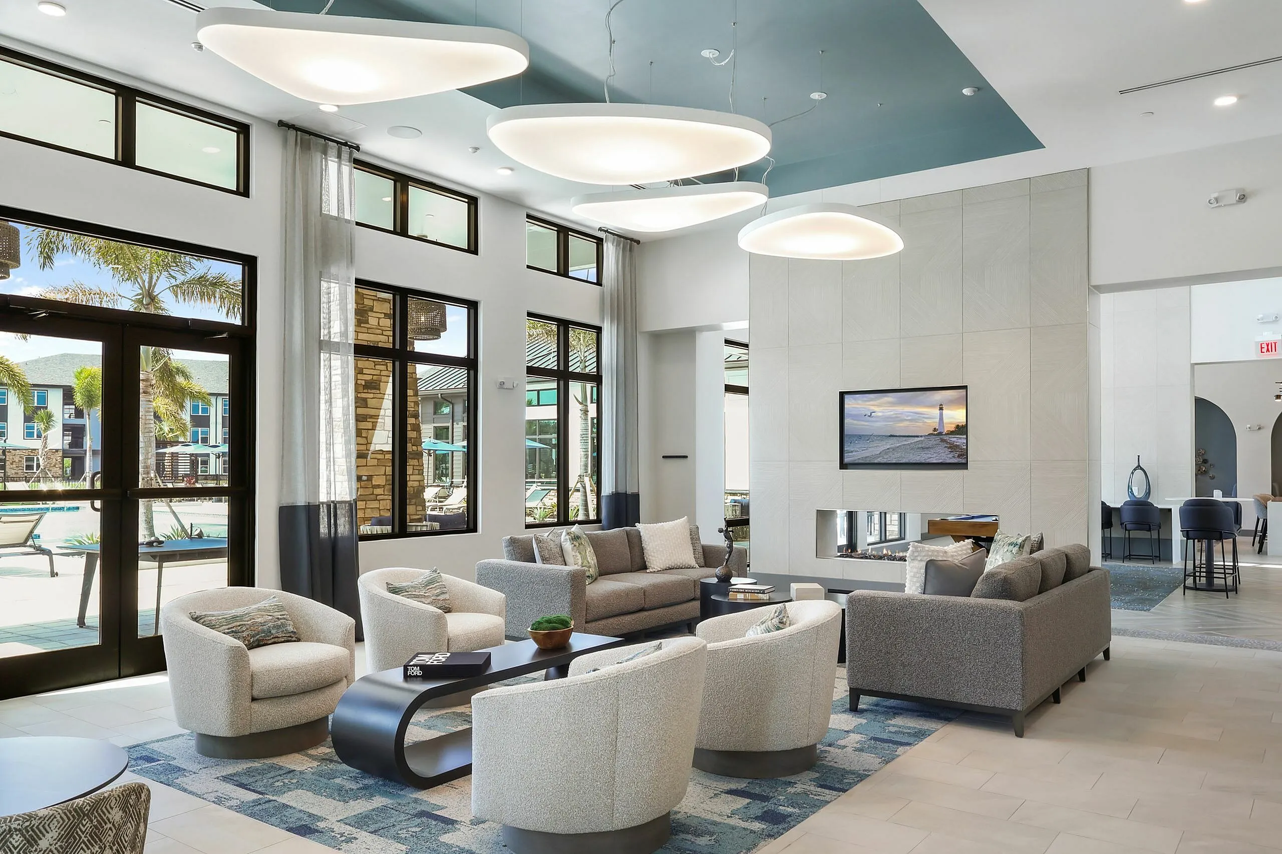 Luxurious modern living room with chic seating area, high ceilings, and expansive windows offering poolside views.