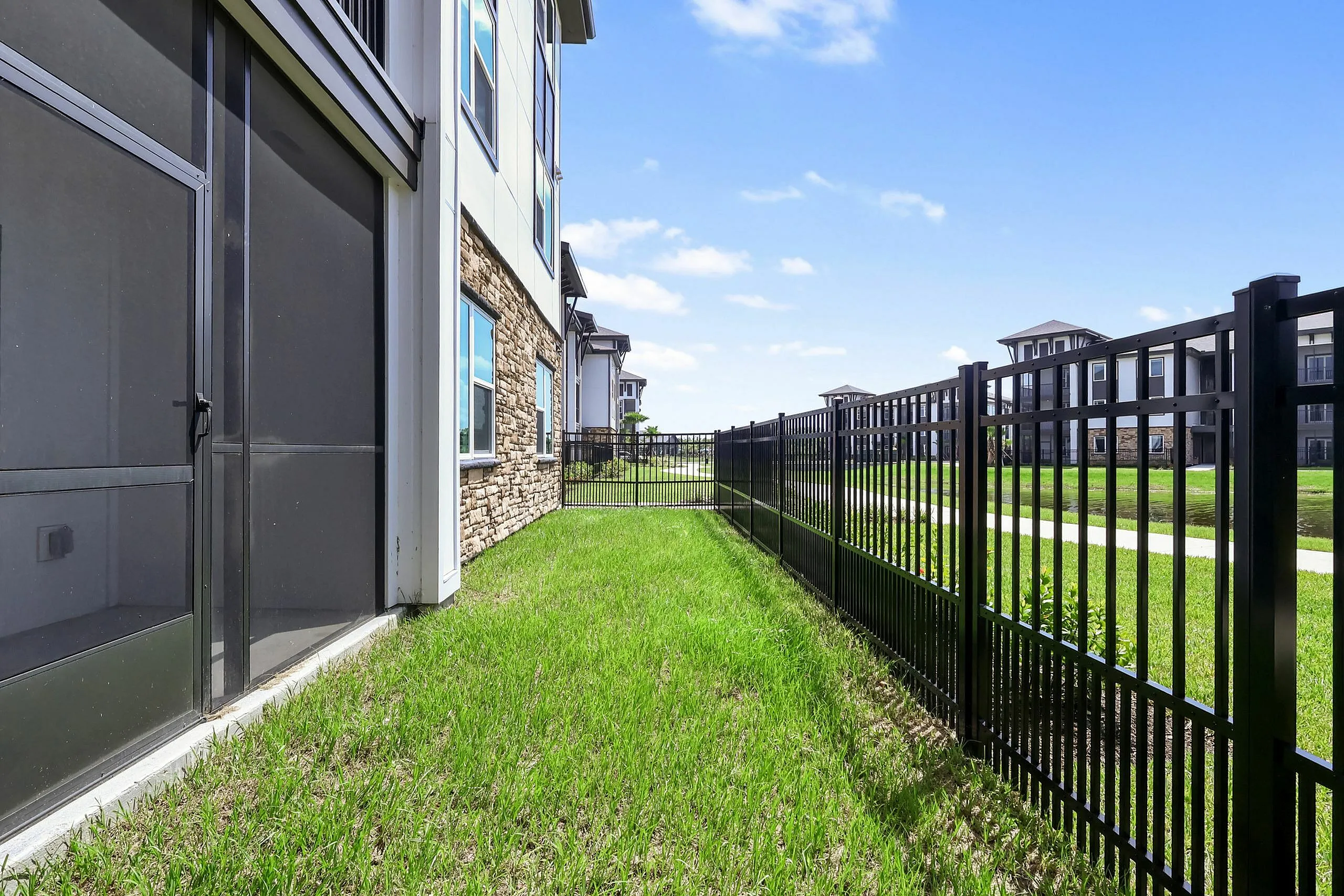 Inviting fenced apartment patio with lush grass and charming stone accents, perfect for relaxation and enjoying sunny days.