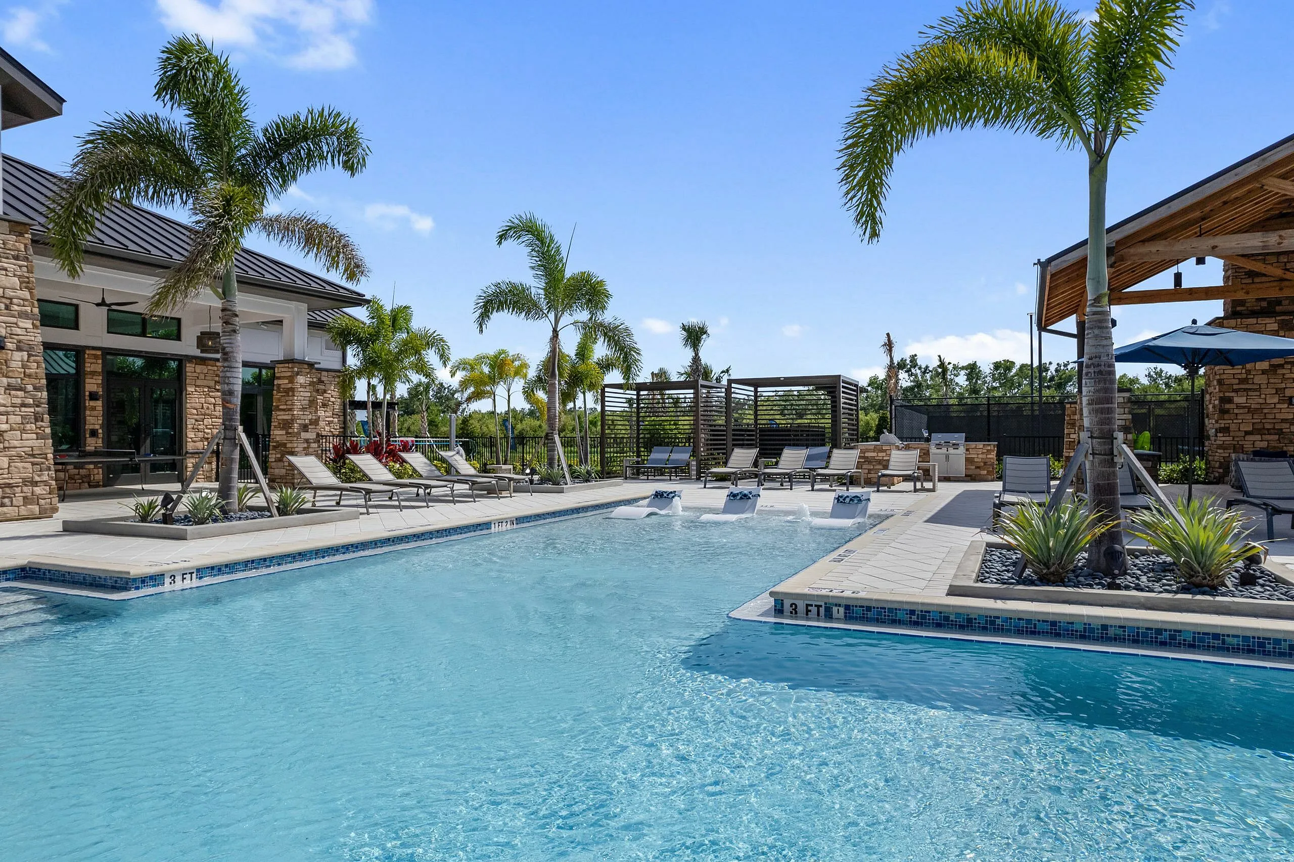 Luxurious outdoor pool area with palm trees, surrounded by elegant stone architecture and comfortable lounge chairs for ultimate relaxation.