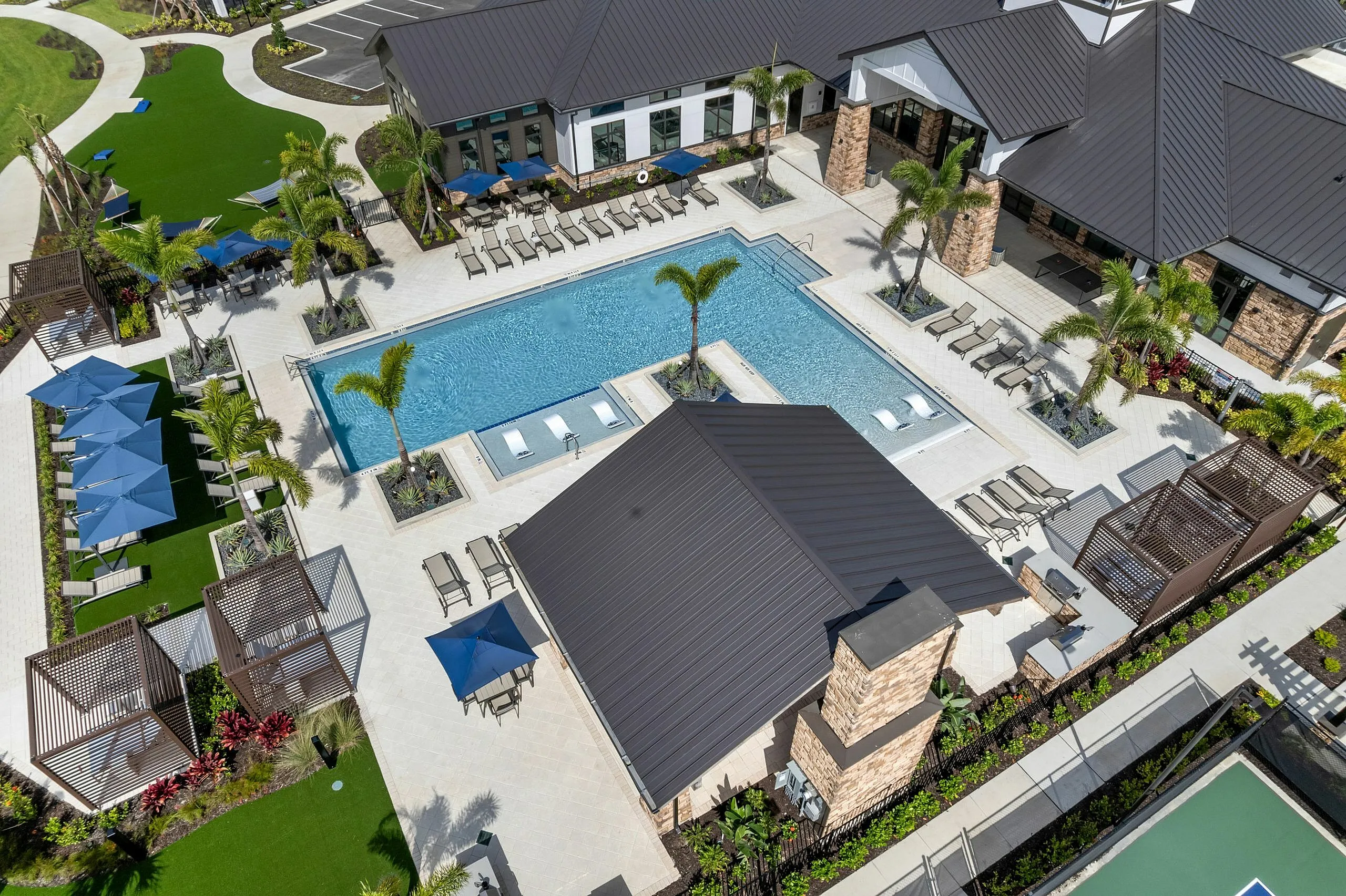 Elegant aerial view of a luxurious pool area with cabanas, sun loungers, and landscaped gardens, perfect for relaxation in a modern apartment complex.