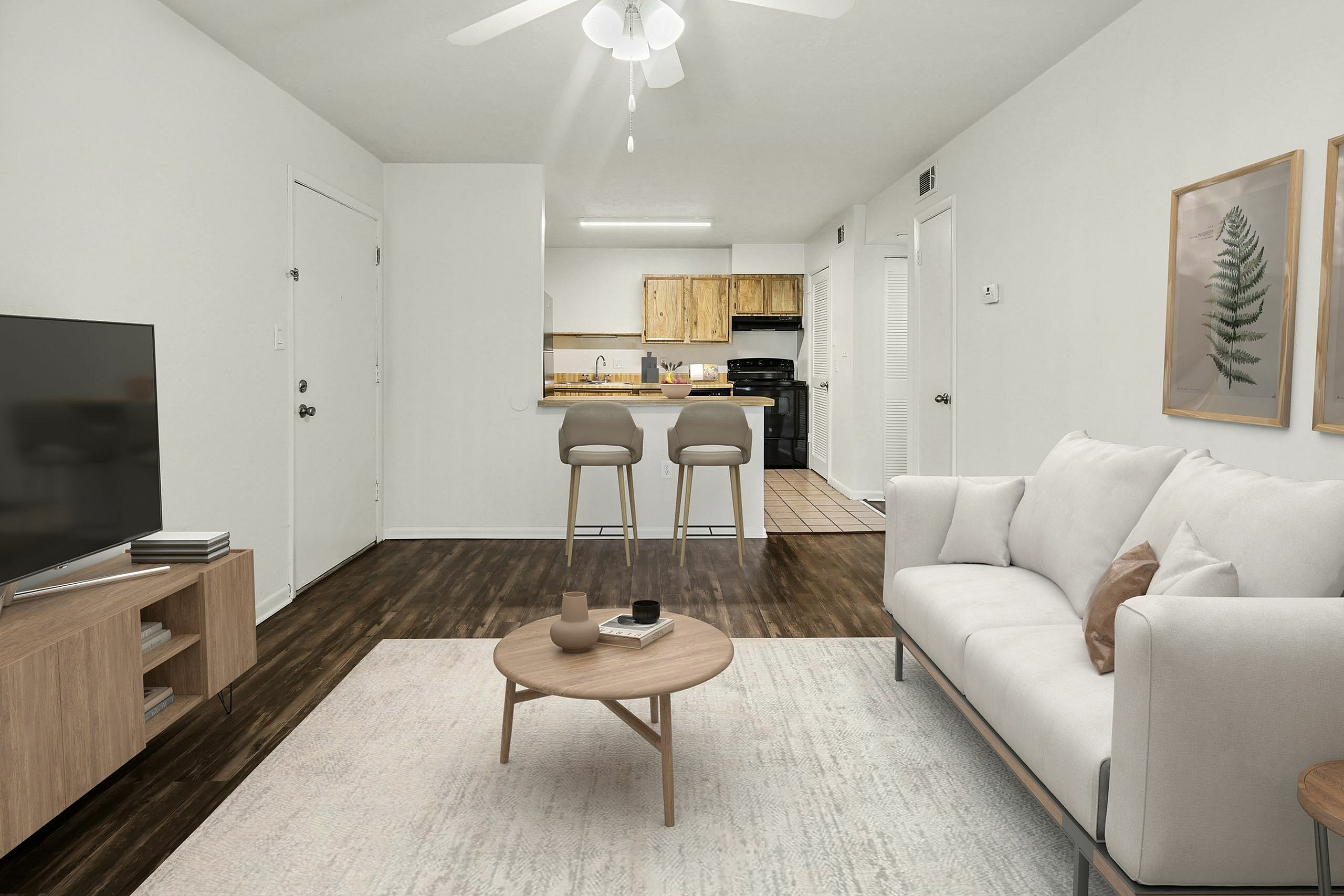 Chic apartment living room with elegant white sofa, cozy coffee table, and a modern open-plan kitchen featuring stylish bar stools and wood accents.