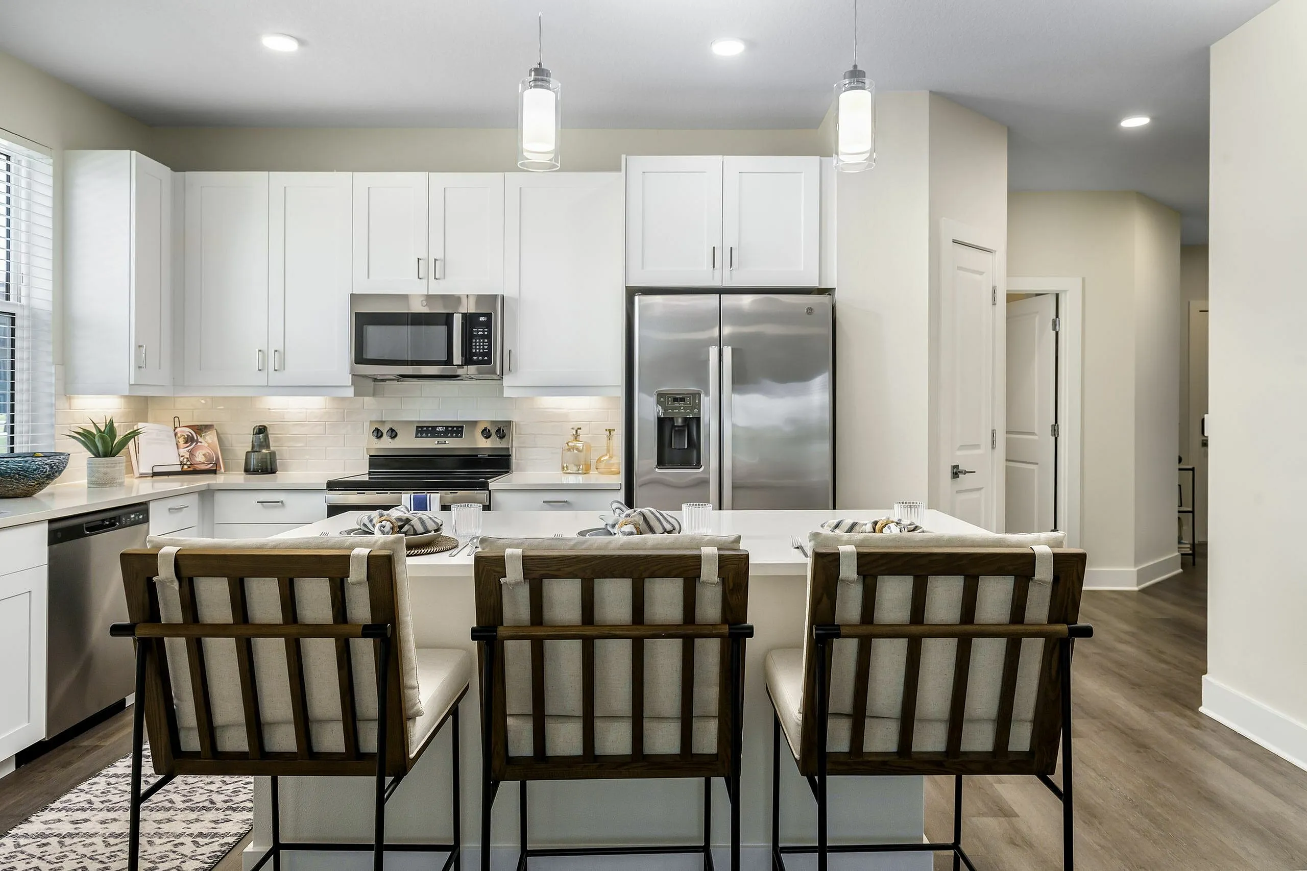 Modern, elegant kitchen with sleek stainless steel appliances, white cabinetry, and a cozy breakfast bar featuring stylish seating.