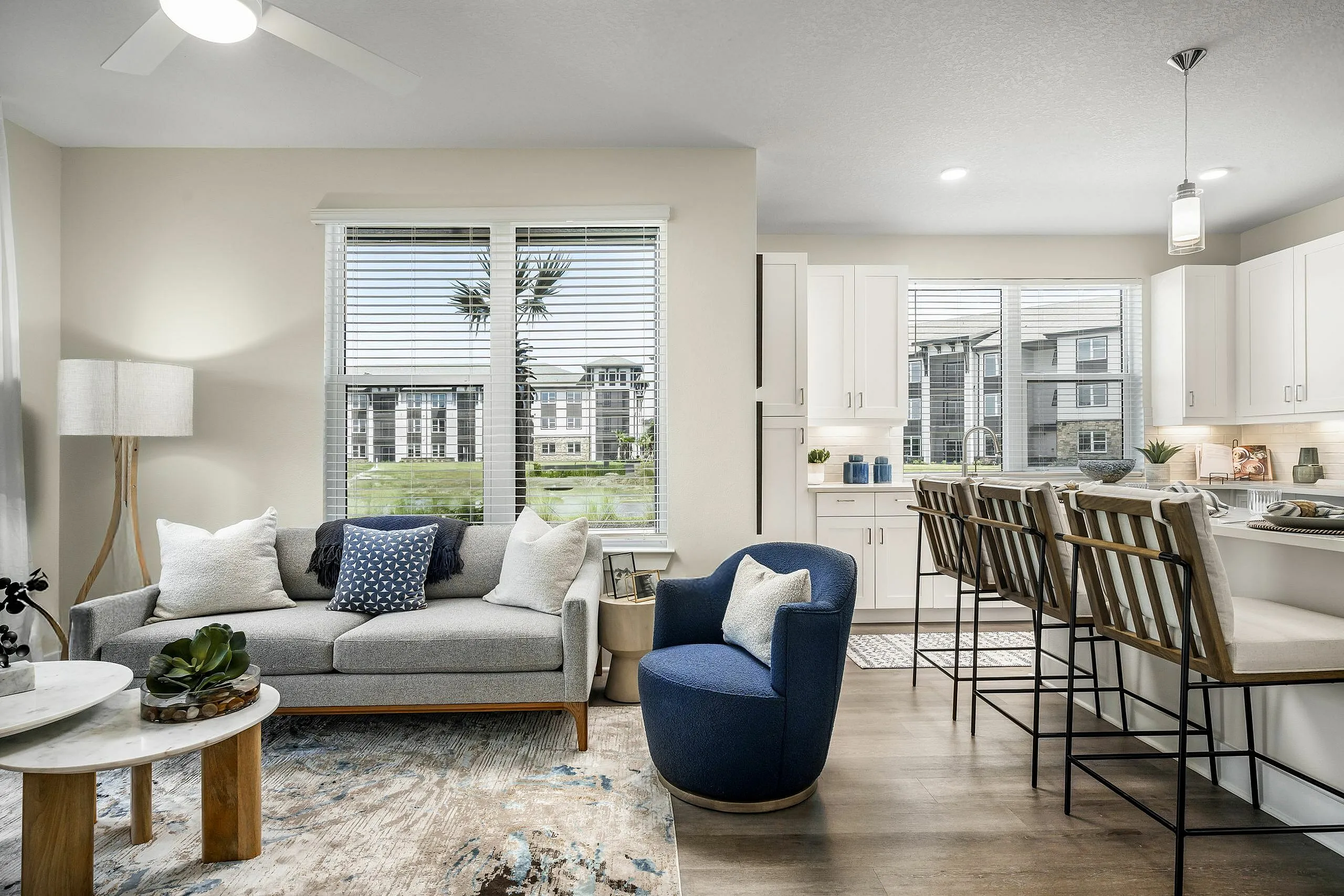 Chic living room with modern furniture, elegant rug, and open kitchen featuring bar seating and ample natural light.