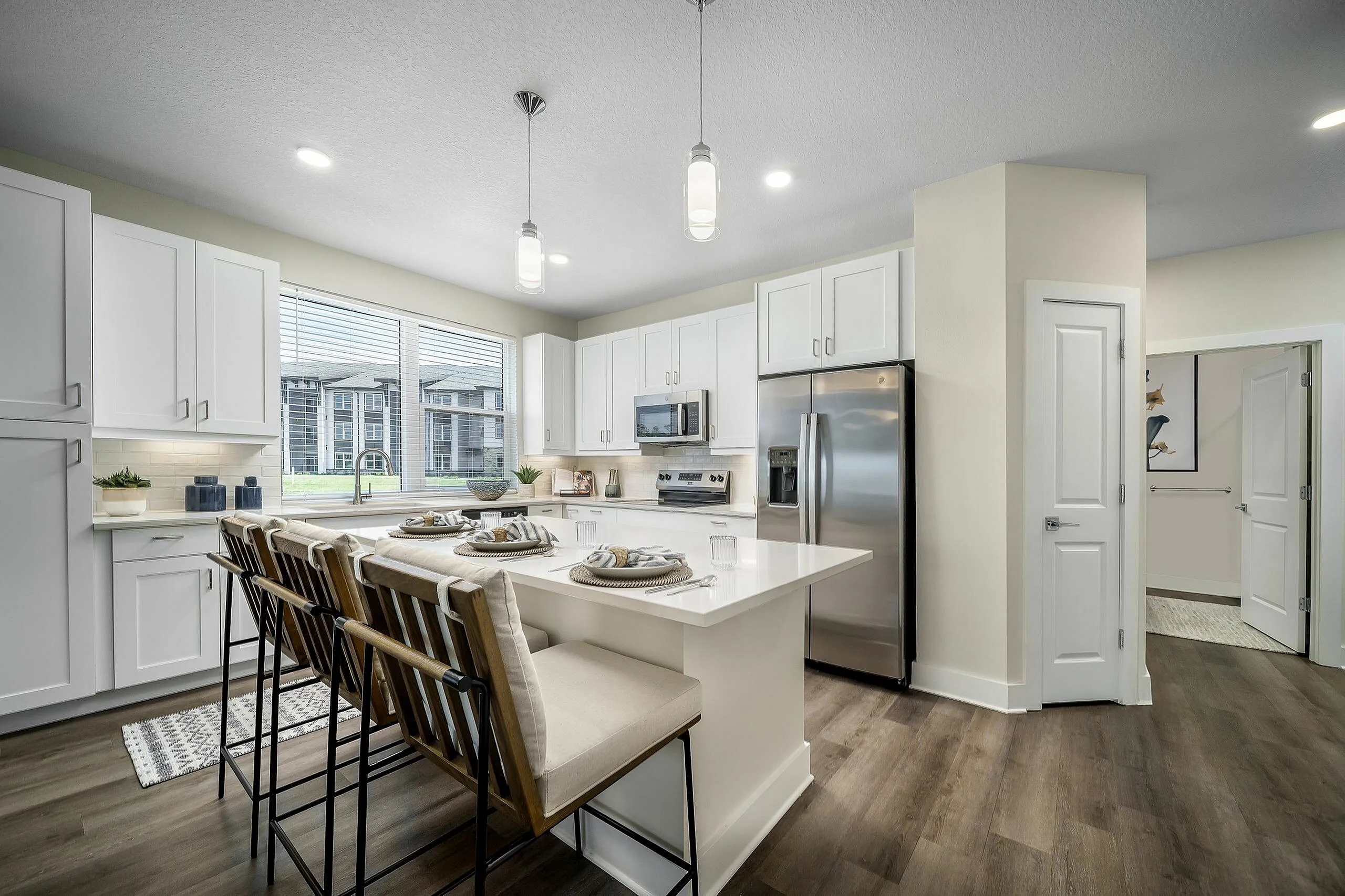Modern kitchen in a luxury apartment showcasing sleek white cabinets, stainless steel appliances, and an inviting breakfast bar with elegant seating.