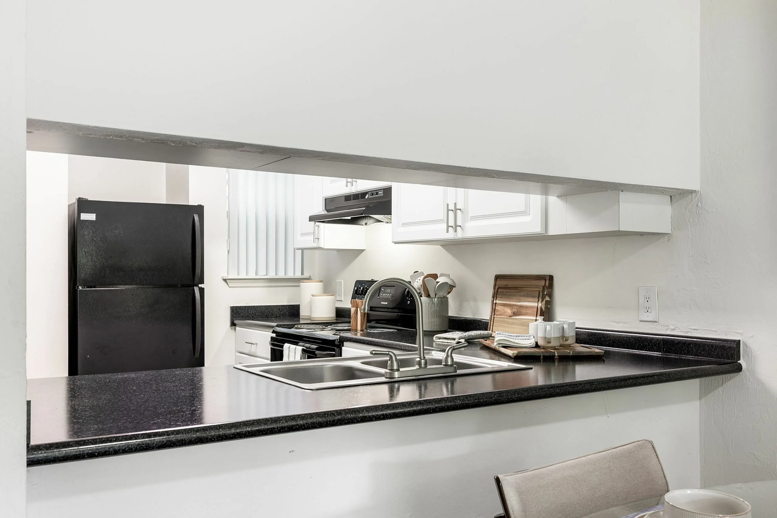 Modern kitchen with sleek black countertops, stainless steel sink, and stylish appliances creating a welcoming culinary space.