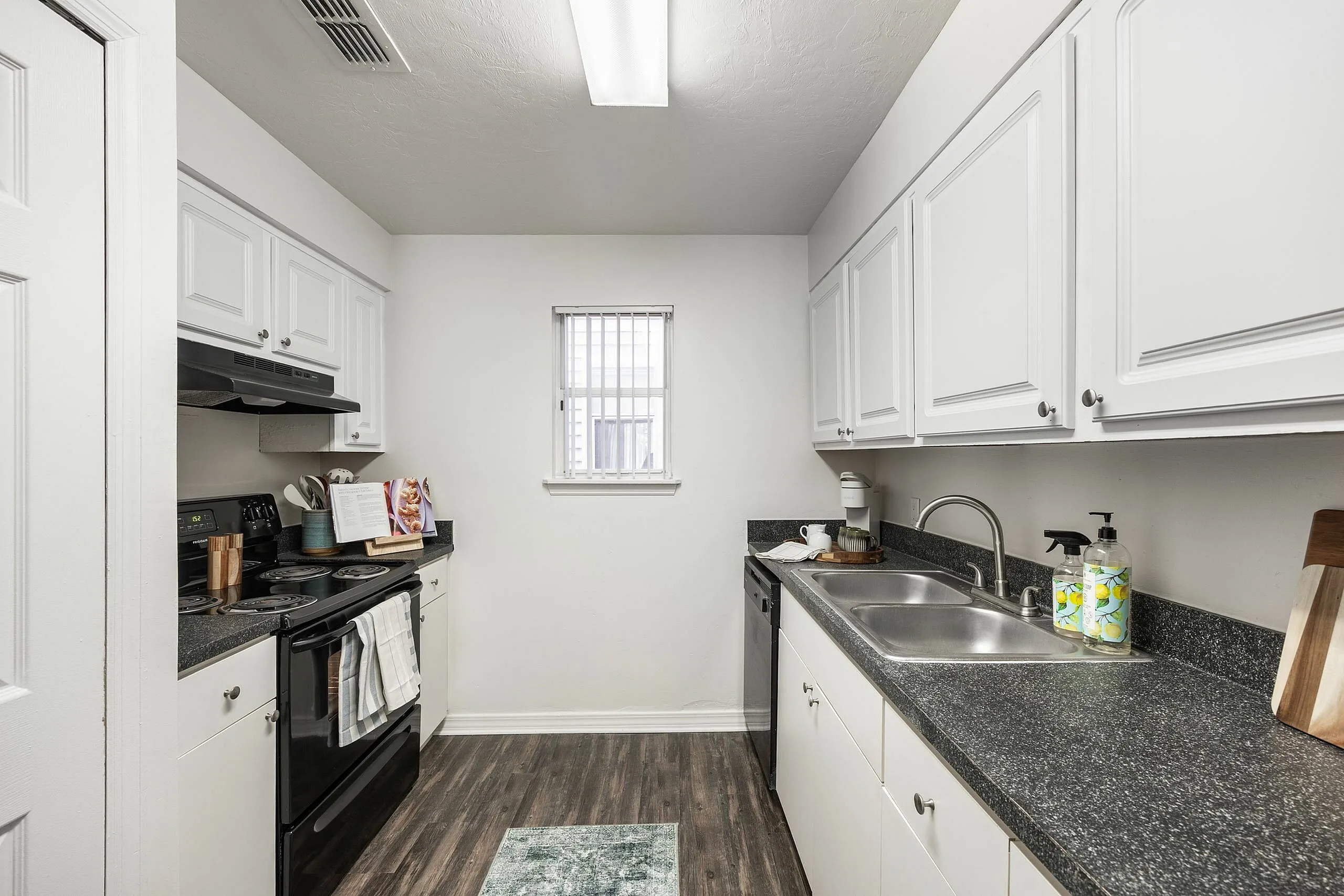 Charming galley kitchen with sleek granite countertops, modern appliances, and contemporary white cabinetry, providing a stylish and efficient cooking space.