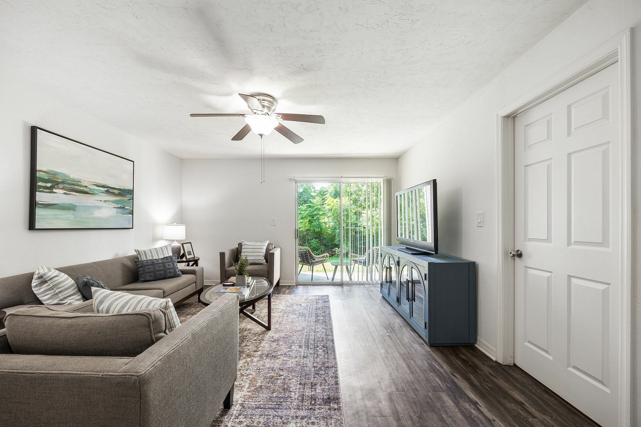 Bright and inviting living room with modern decor, featuring a cozy sofa, stylish coffee table, and large window overlooking a lush garden.