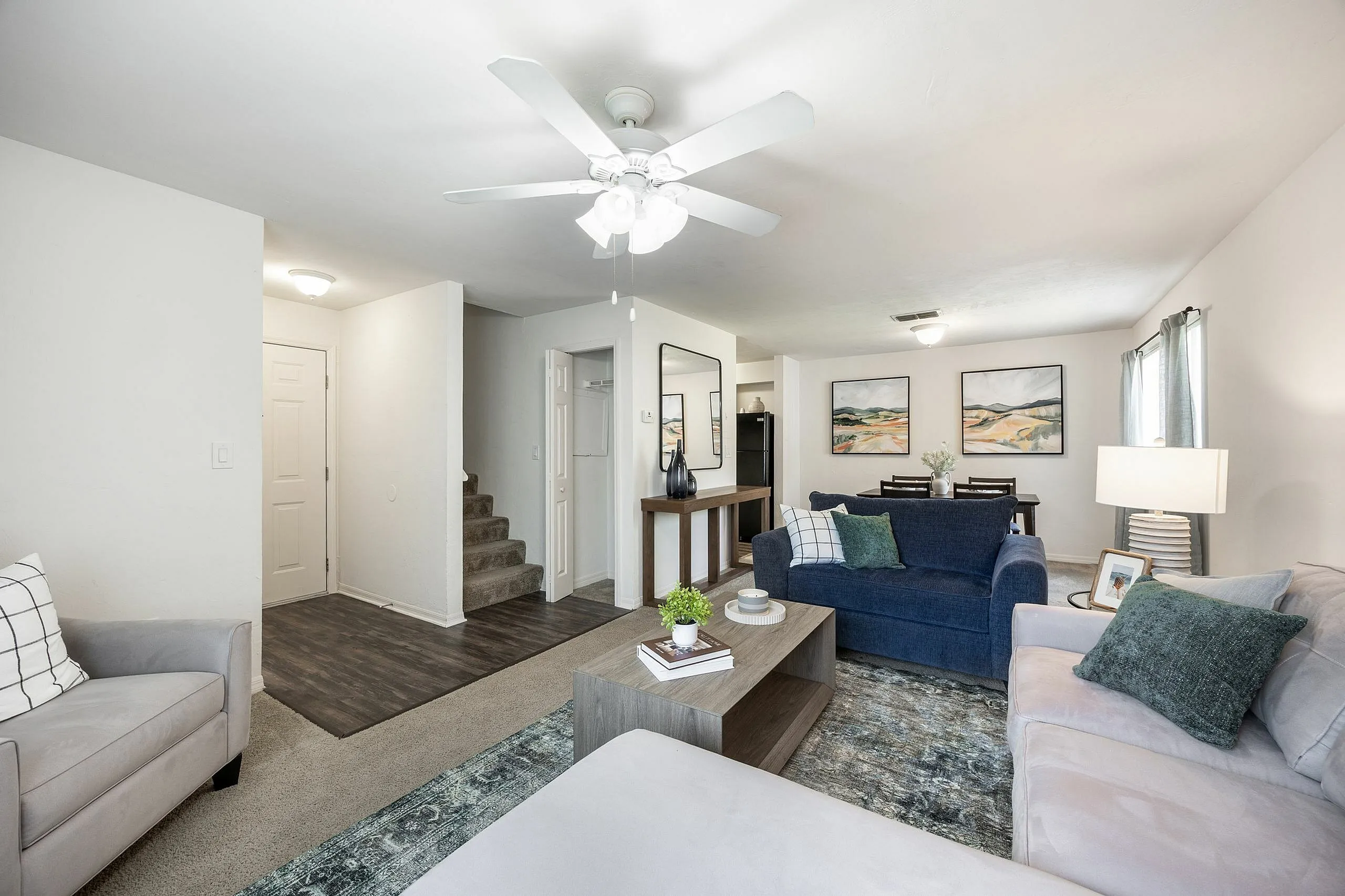 Inviting living room with modern decor, featuring cozy sofas, a stylish coffee table, and vibrant wall art, leading to a chic dining area.