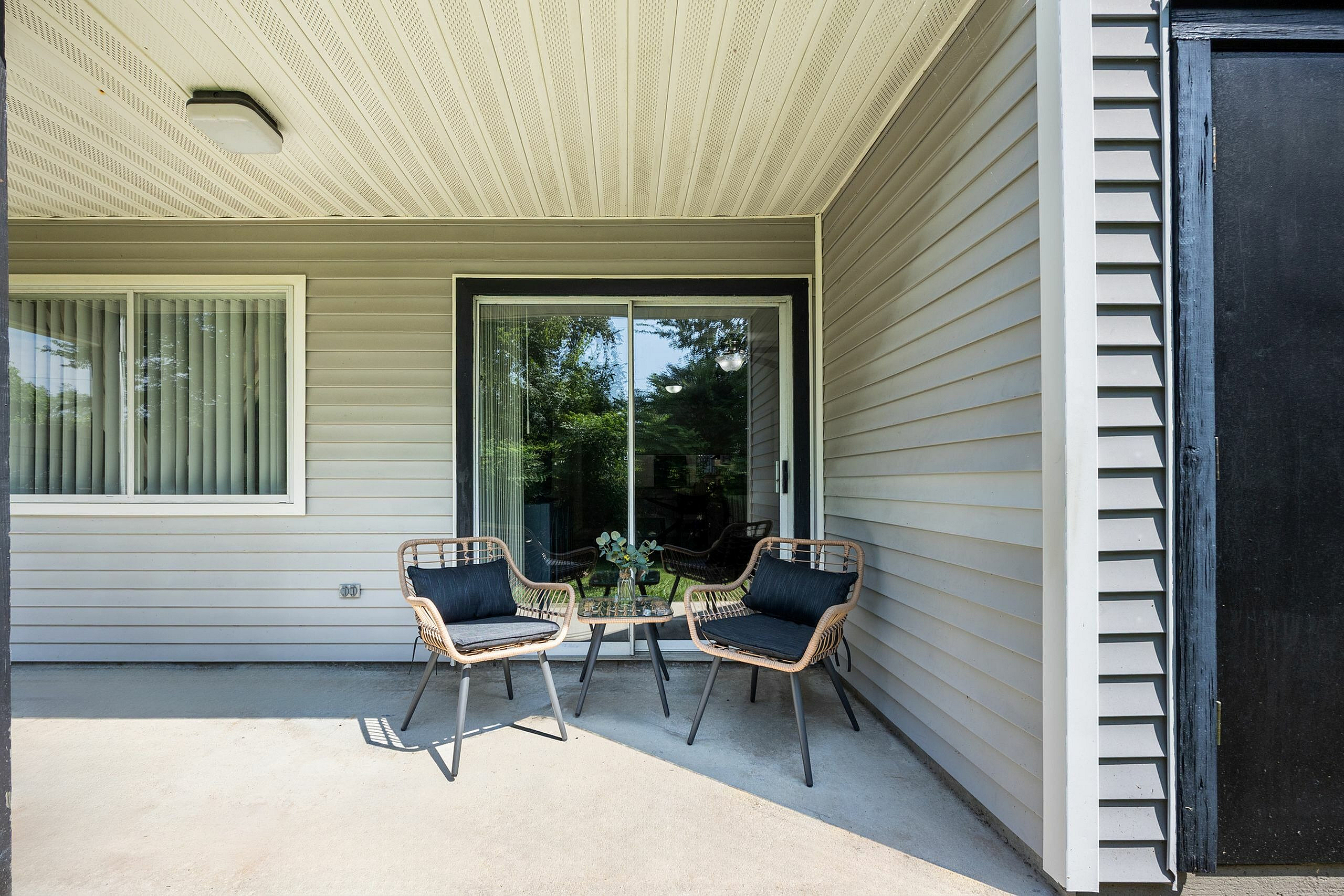 Charming porch with modern wicker chairs and a small table, perfect for relaxing and enjoying the outdoors.