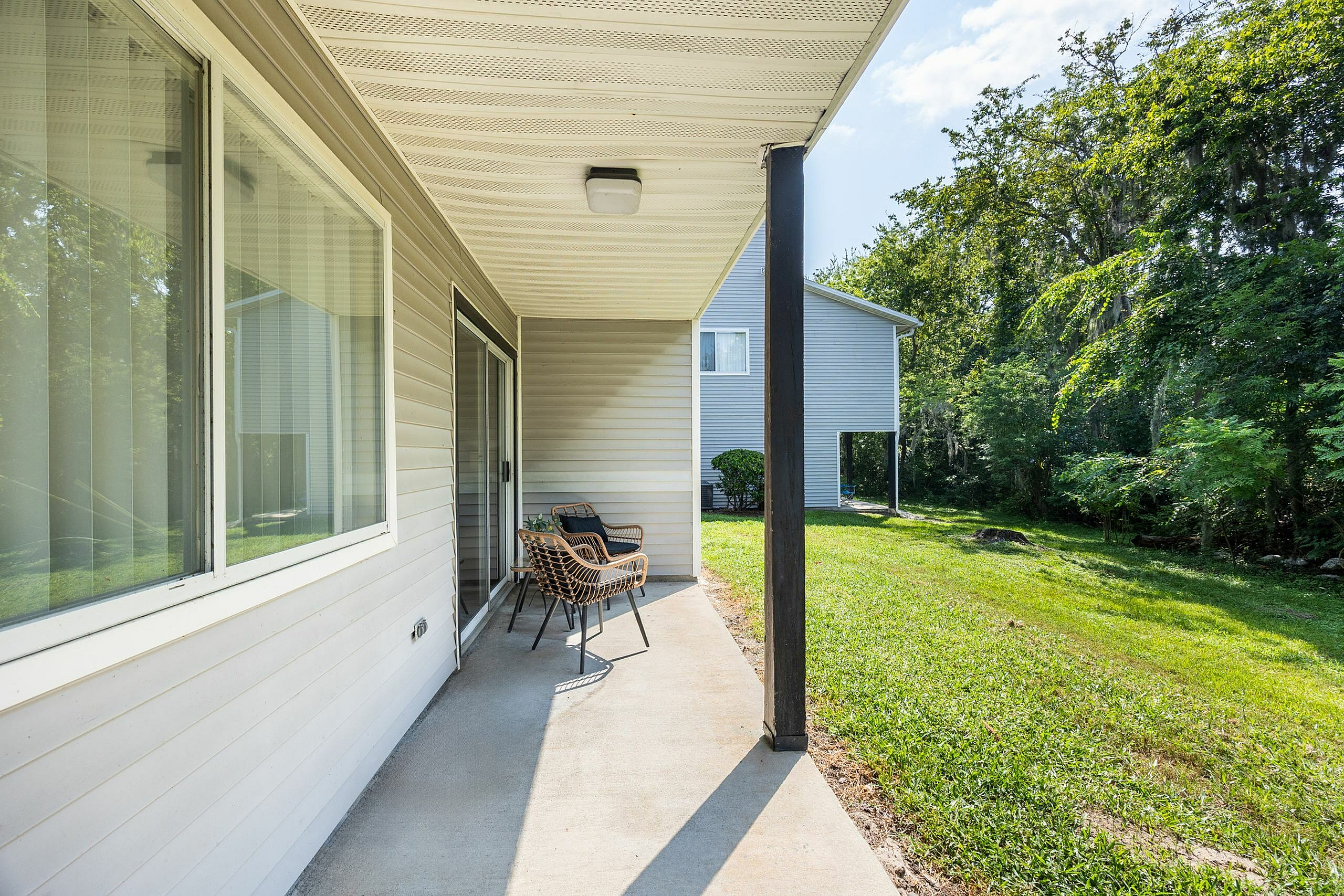 Inviting patio with modern seating overlooking a lush green yard, perfect for relaxation and outdoor enjoyment.