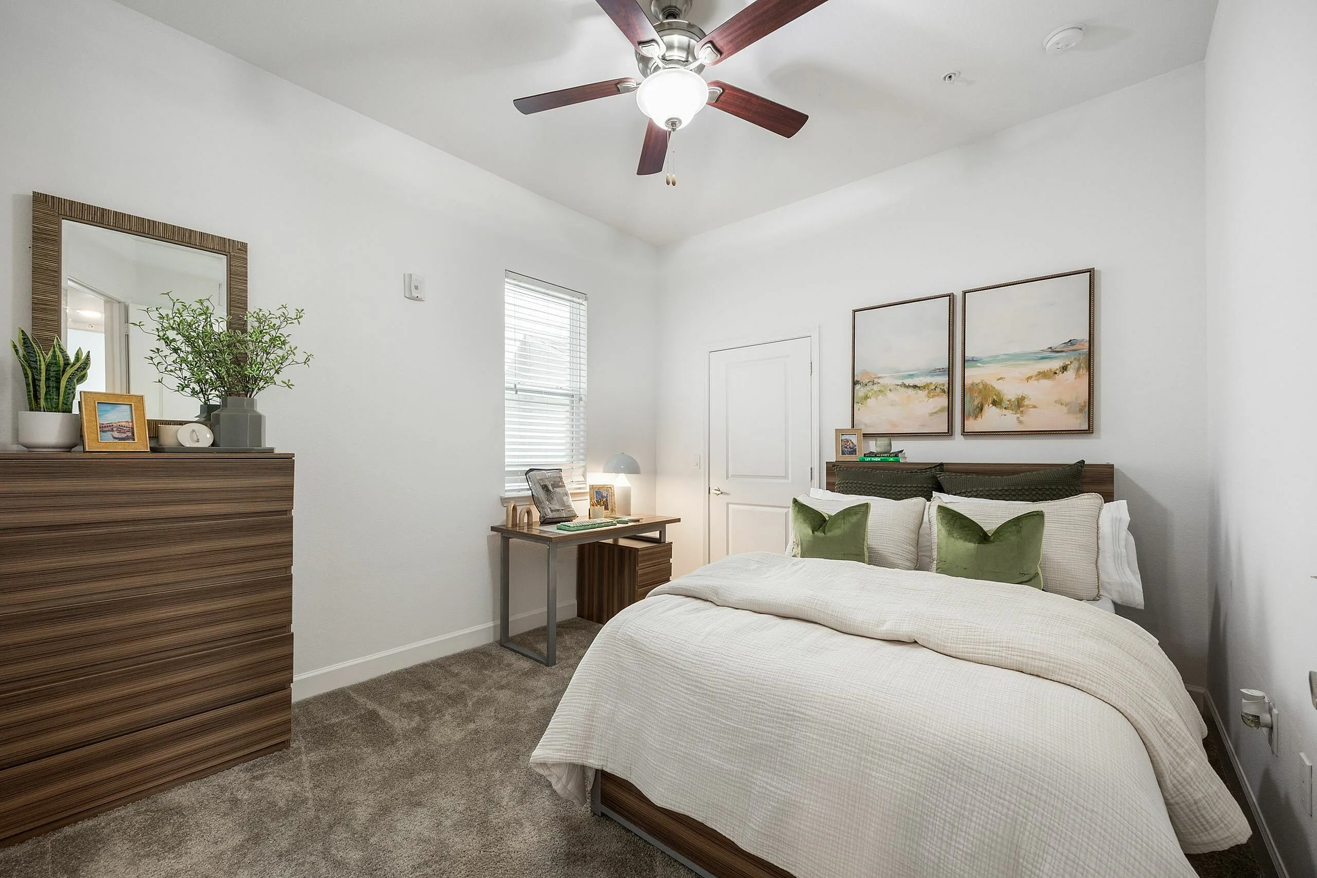 Tranquil bedroom featuring elegant wooden furniture, plush bedding with green accents, and serene artwork creating a cozy retreat.