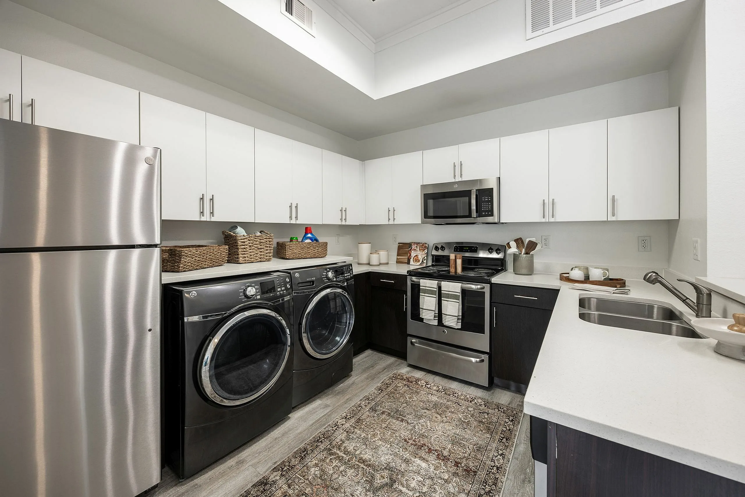 Modern kitchen showcasing sleek stainless steel appliances, a convenient washer and dryer, stylish cabinetry, and ample counter space.